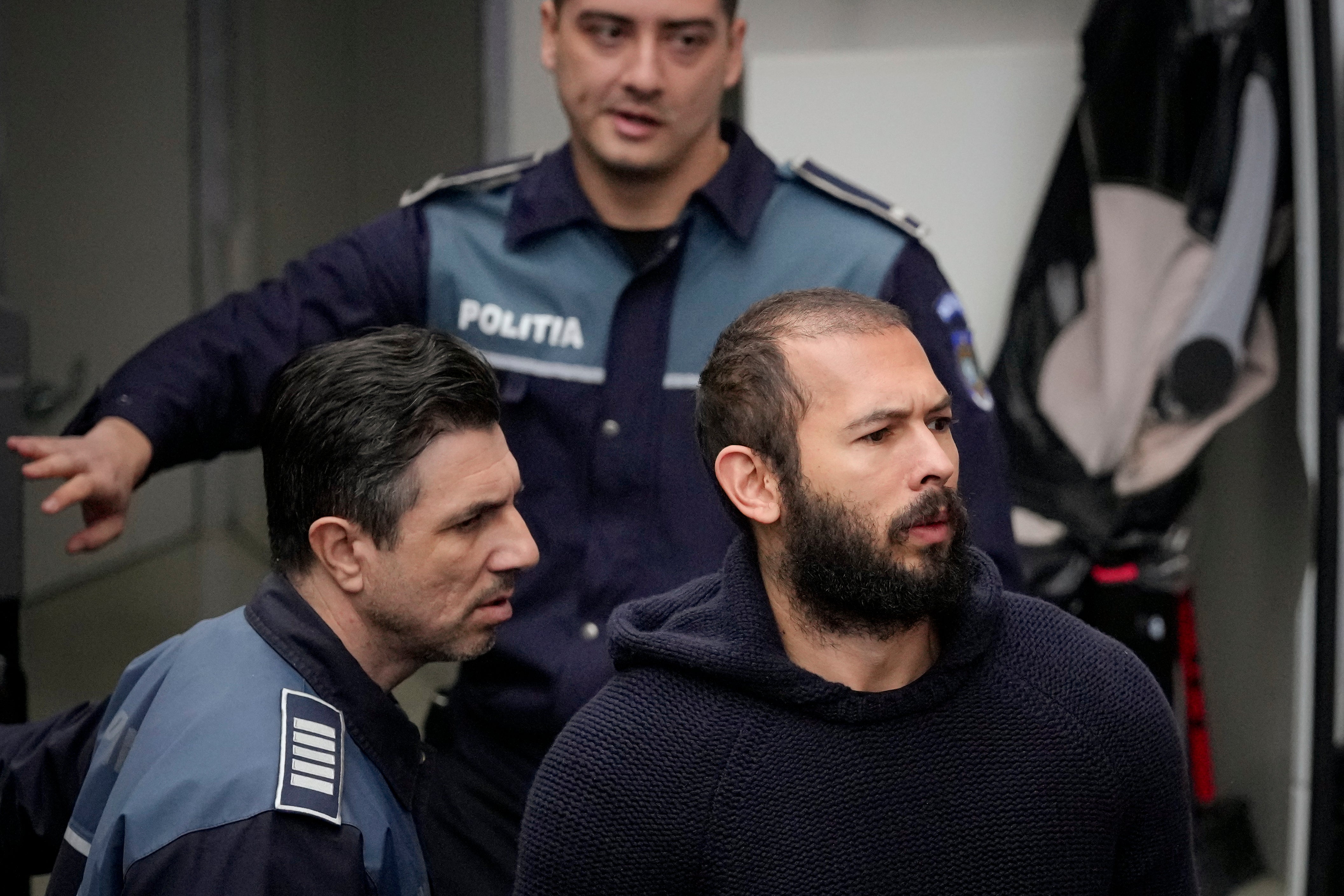 Police officers escort Andrew Tate, center, handcuffed to his brother Tristan Tate, to the Court of Appeal in Bucharest