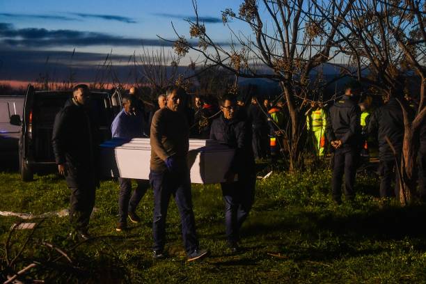 Funeral parlour employees carry away coffins containing the bodies of deceased migrants on 26 February 2023