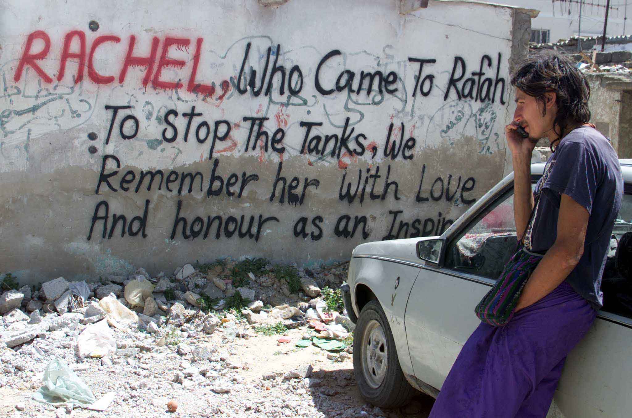 A peace activist in front of graffiti about Corrie on the Gaza Strip