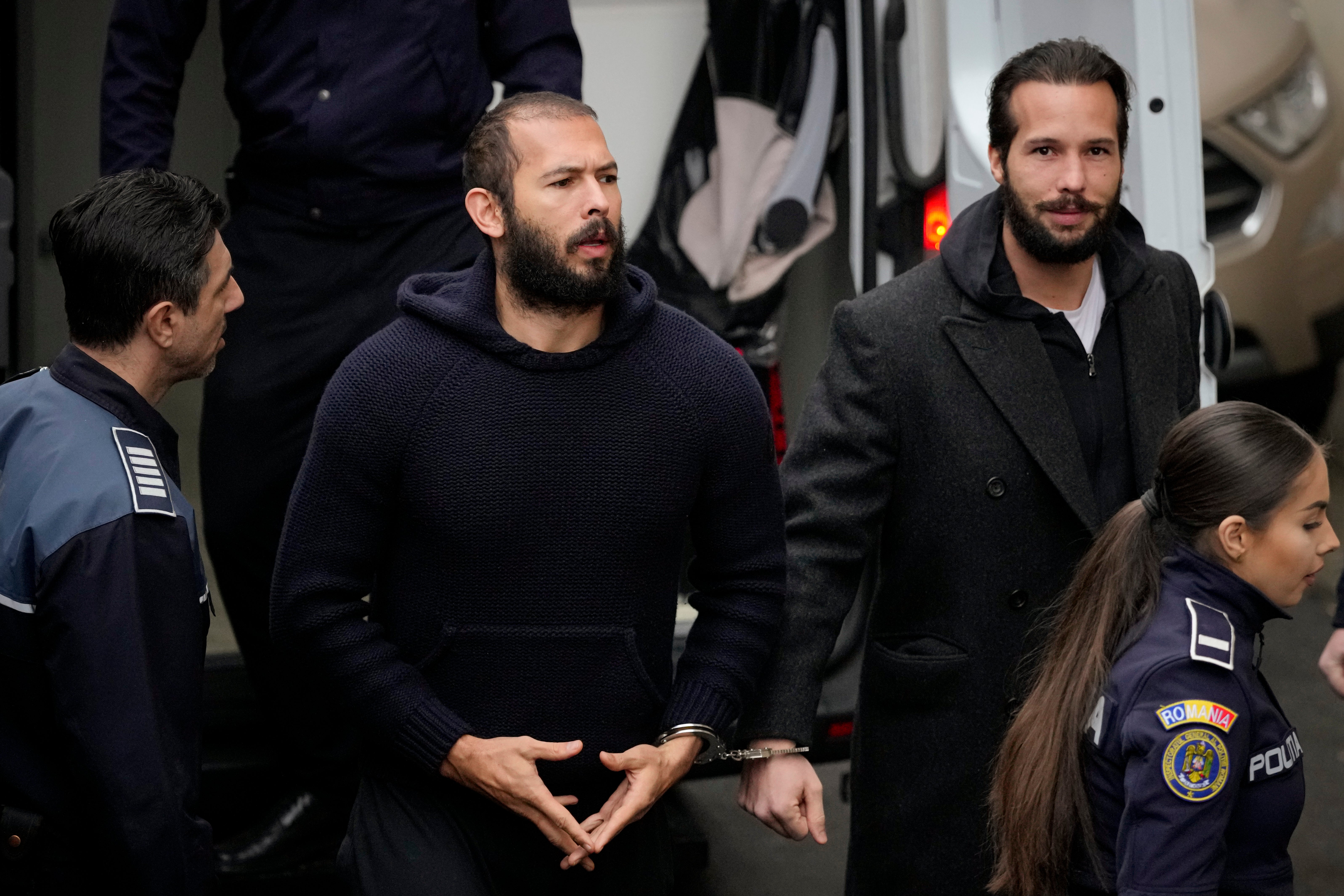 Officers escort Andrew Tate, centre, and his brother Tristan Tate to the Court of Appeal in Bucharest