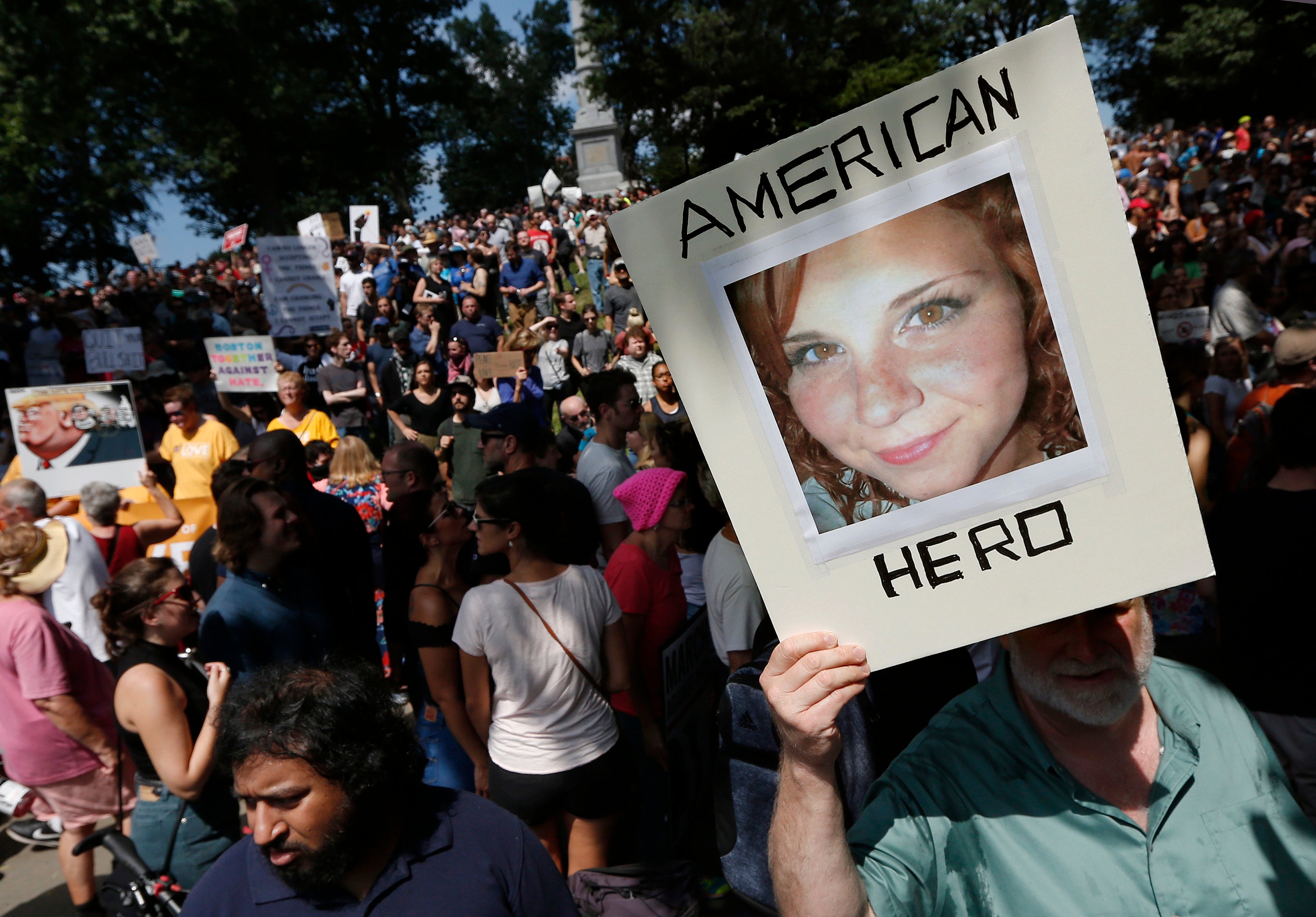 FILE -n this 2017, file photo, a protester holds a photo of Heather Heyer on Boston Common at a Free Speech rally organized by conservative activists in Boston