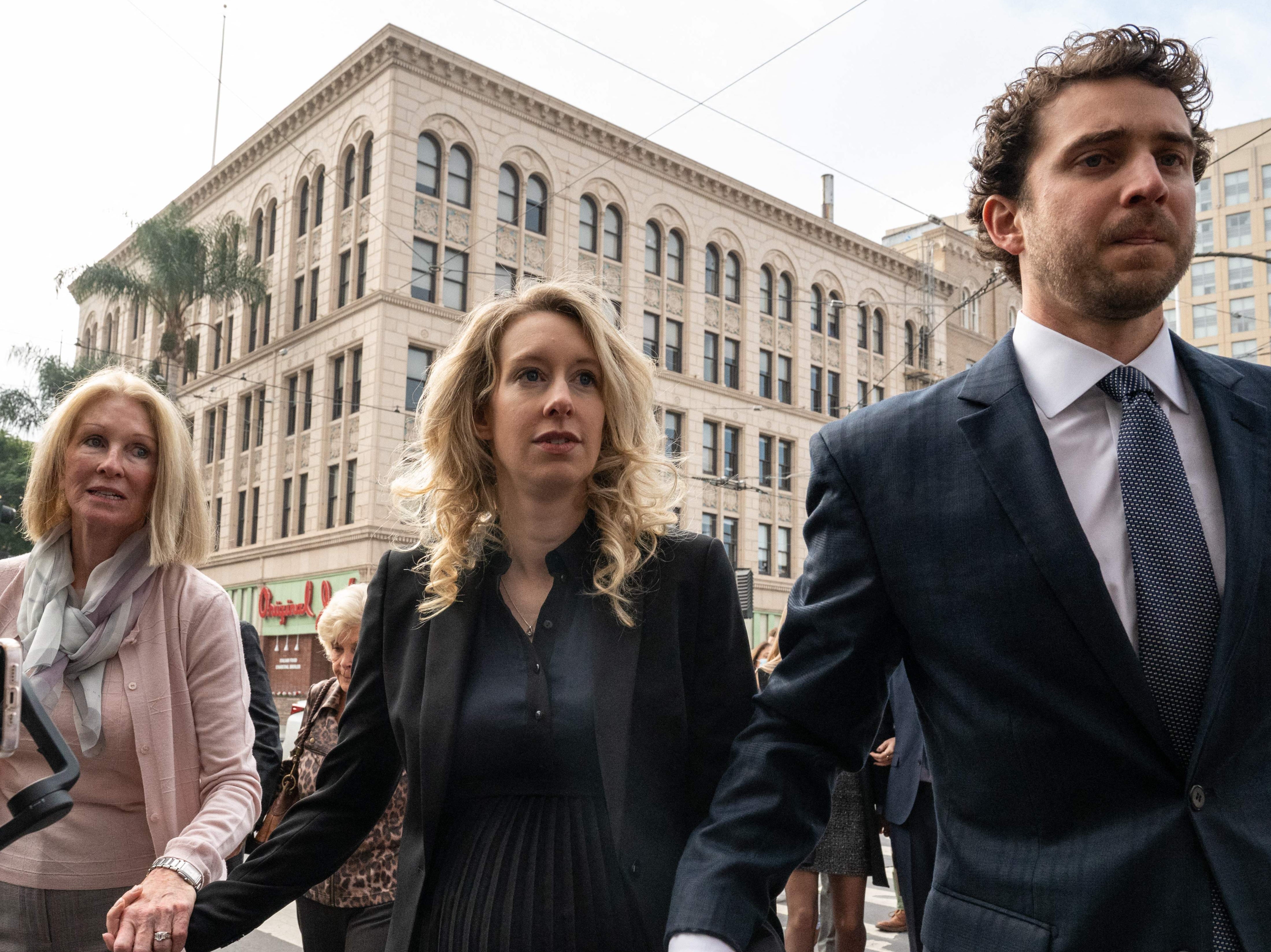 Elizabeth Holmes (C), founder and former CEO of blood testing and life sciences company Theranos, walks with her mother Noel Holmes and partner Billy Evans into the federal courthouse for her sentencing hearing on November 18, 2022 in San Jose, California