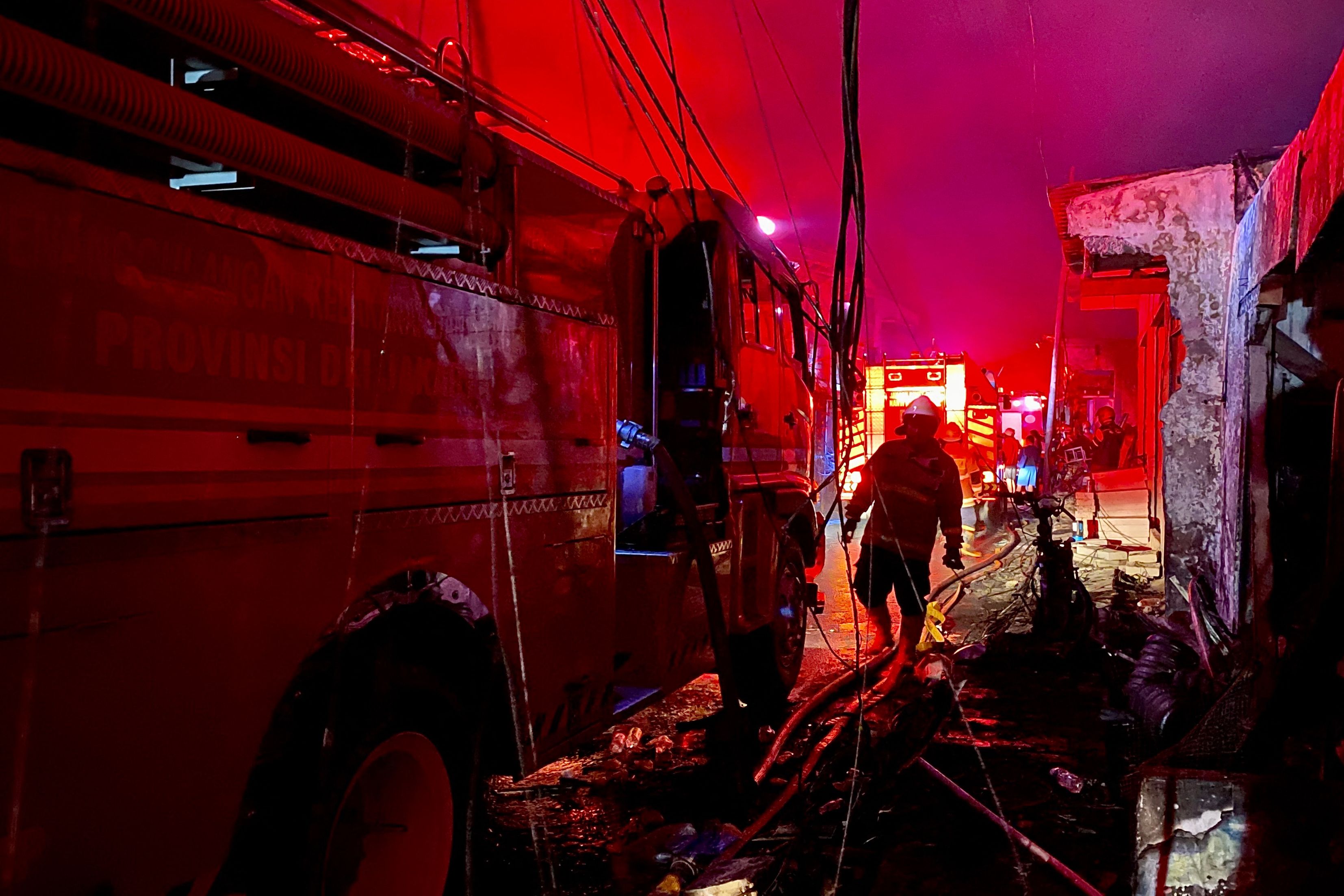 Firefighters extinguish fires that burn down homes of residents living nearby of the fire at the fuel depot owned by the state-owned oil and gas company Pertamina, in Plumpang, Jakarta, on 3 March 2023