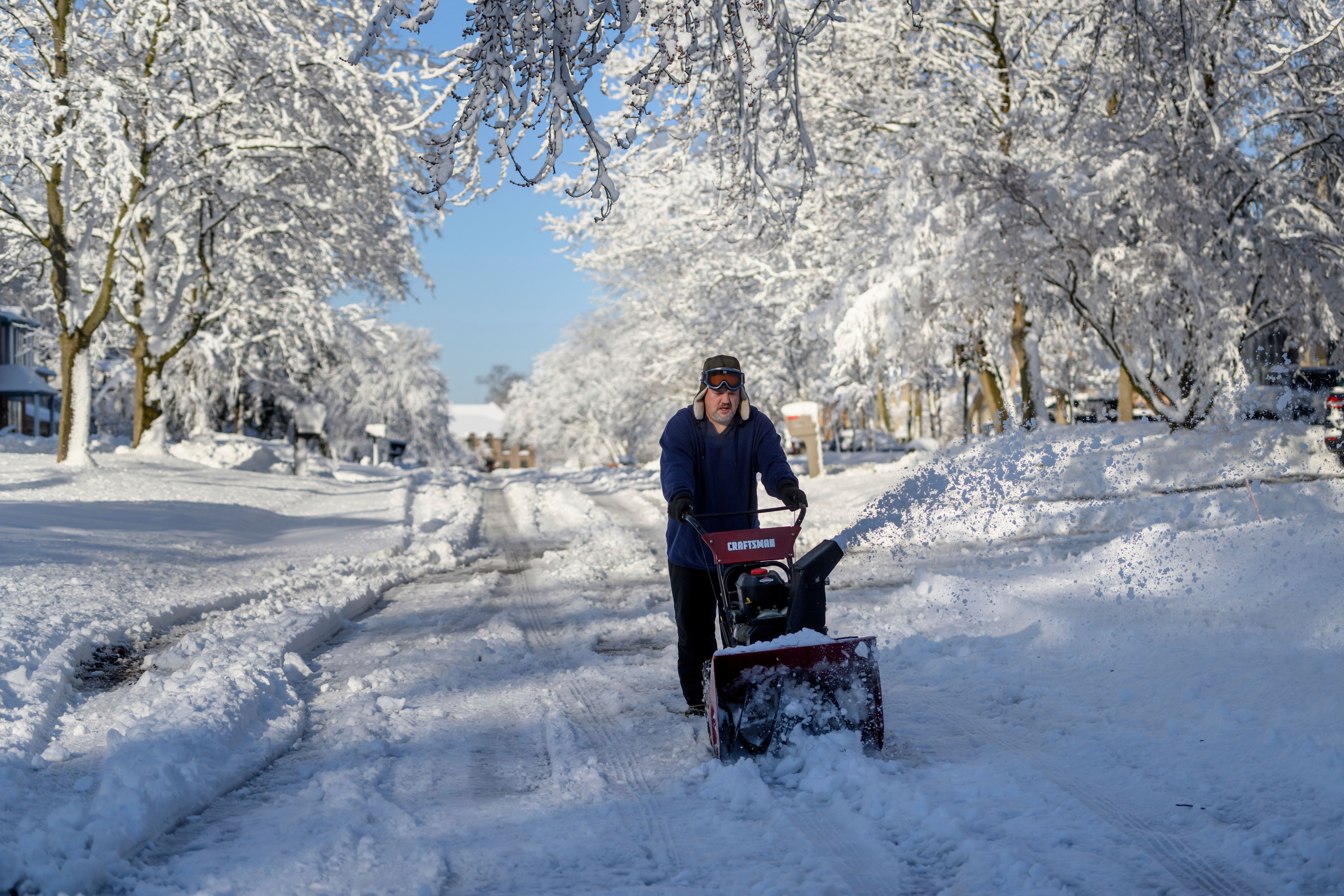 Ross Weaver plows out a section of road in front of his home in Farmington Hills, Michigan, on Saturday after a winter storm left several inches of snow across the Metro Detroit area.