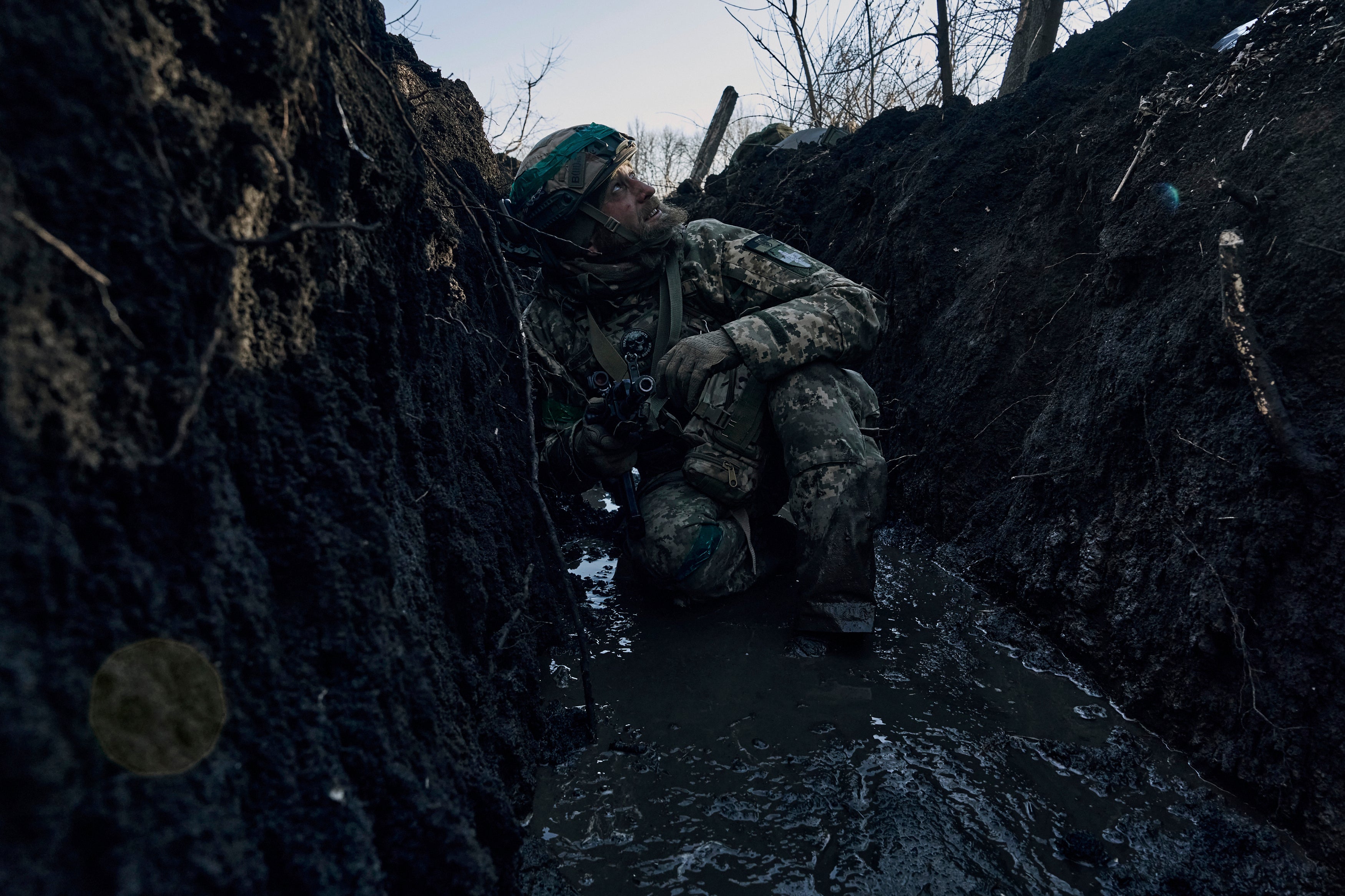 A Ukrainian soldier takes cover in a trench under Russian shelling on the frontline close to Bakhmut, in the region of Donetsk