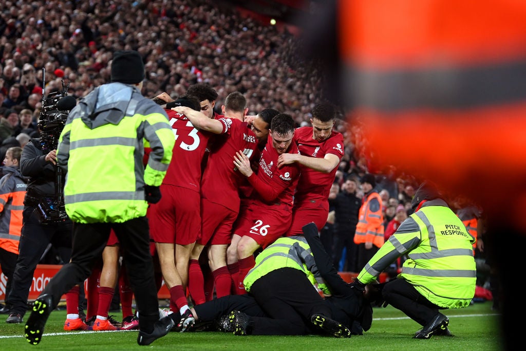 A pitch invader is tackled by stewards after colliding with Liverpool player Andy Robertson