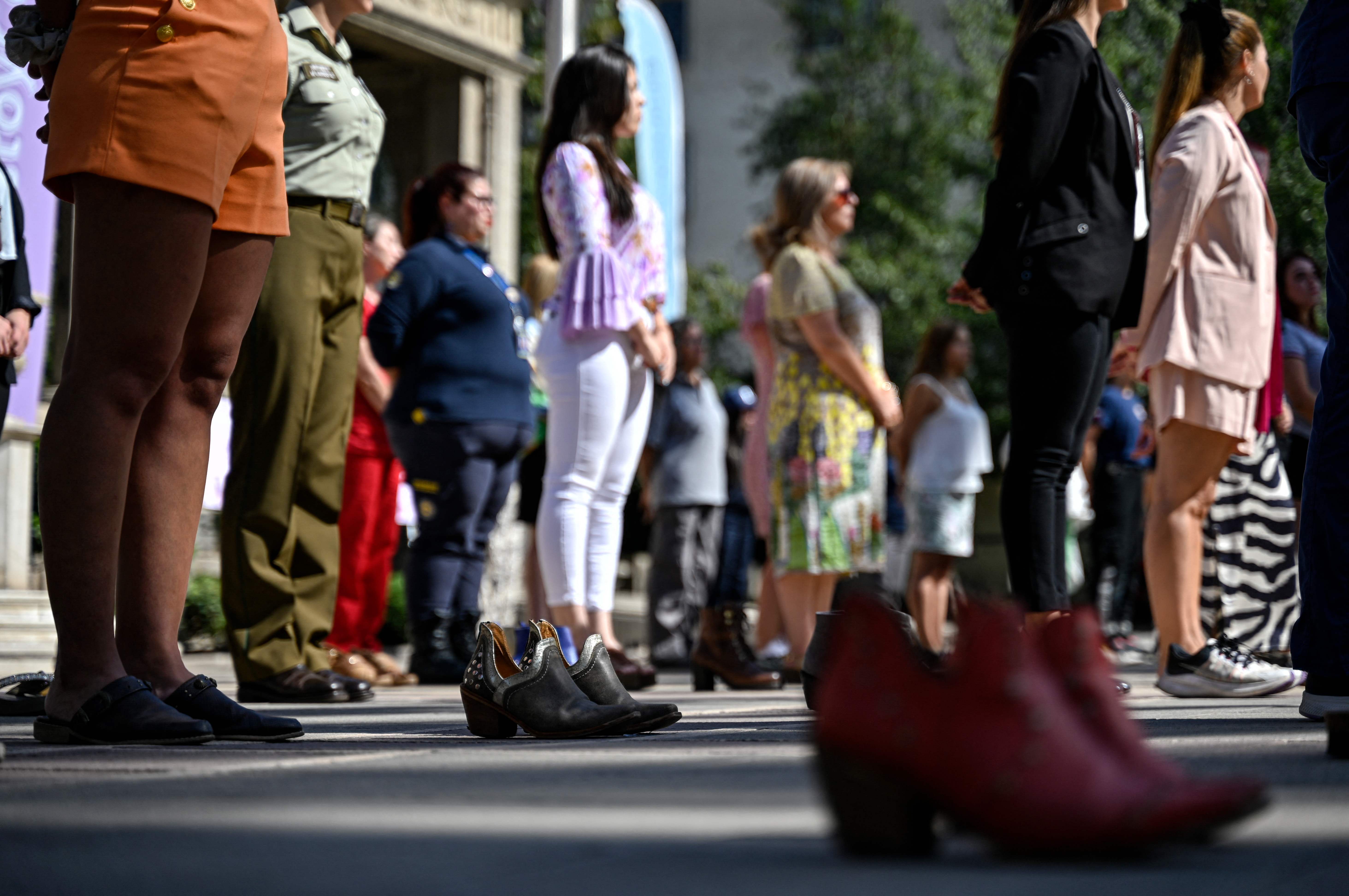 Women from different labour sectors pose together during the "100 Shoes" intervention to pay tribute to women who were victims of violence, in front of the Falabella Palace in Santiago