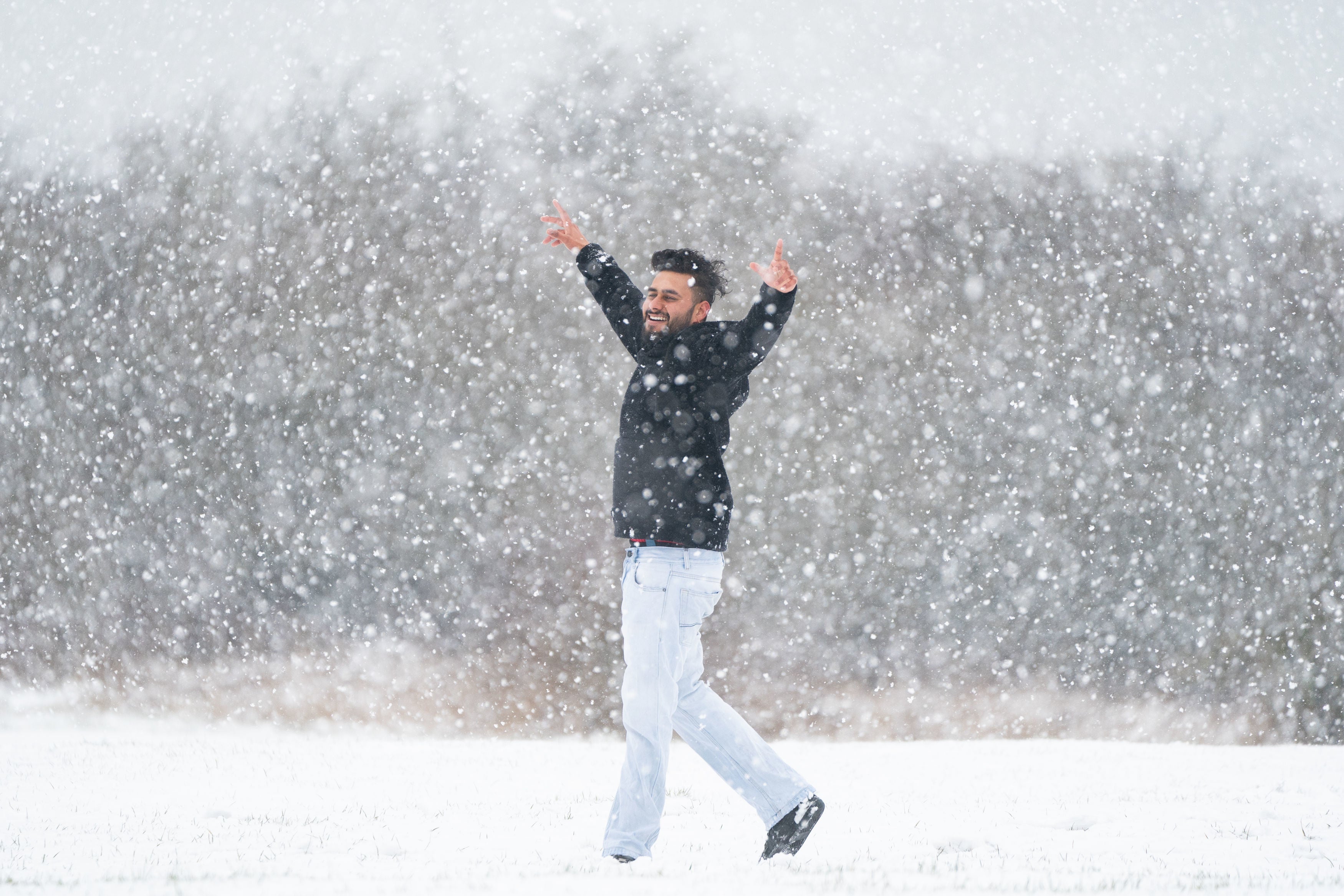 A man raises his arms in the snow on the Dunstable Downs in Bedfordshire