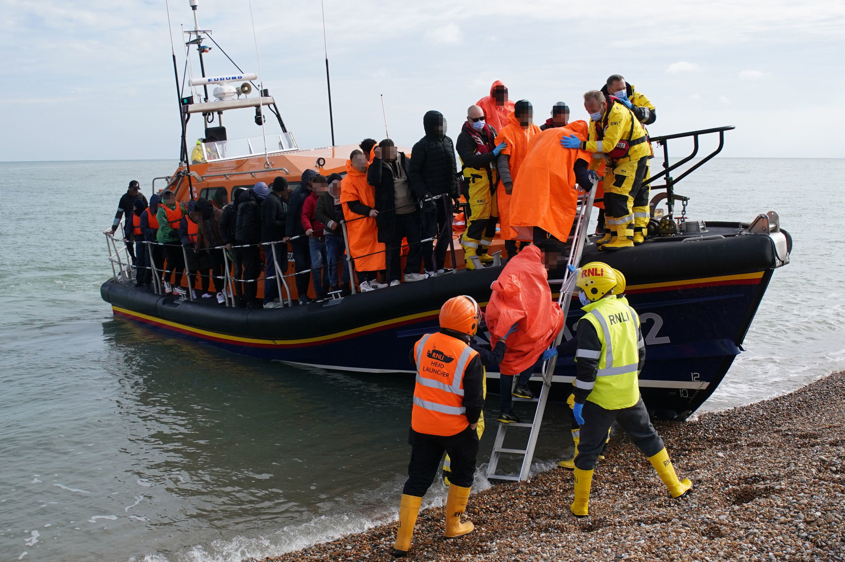 A group of people thought to be migrants are brought in to Dungeness beach by a lifeboat crew following an incident in the channel