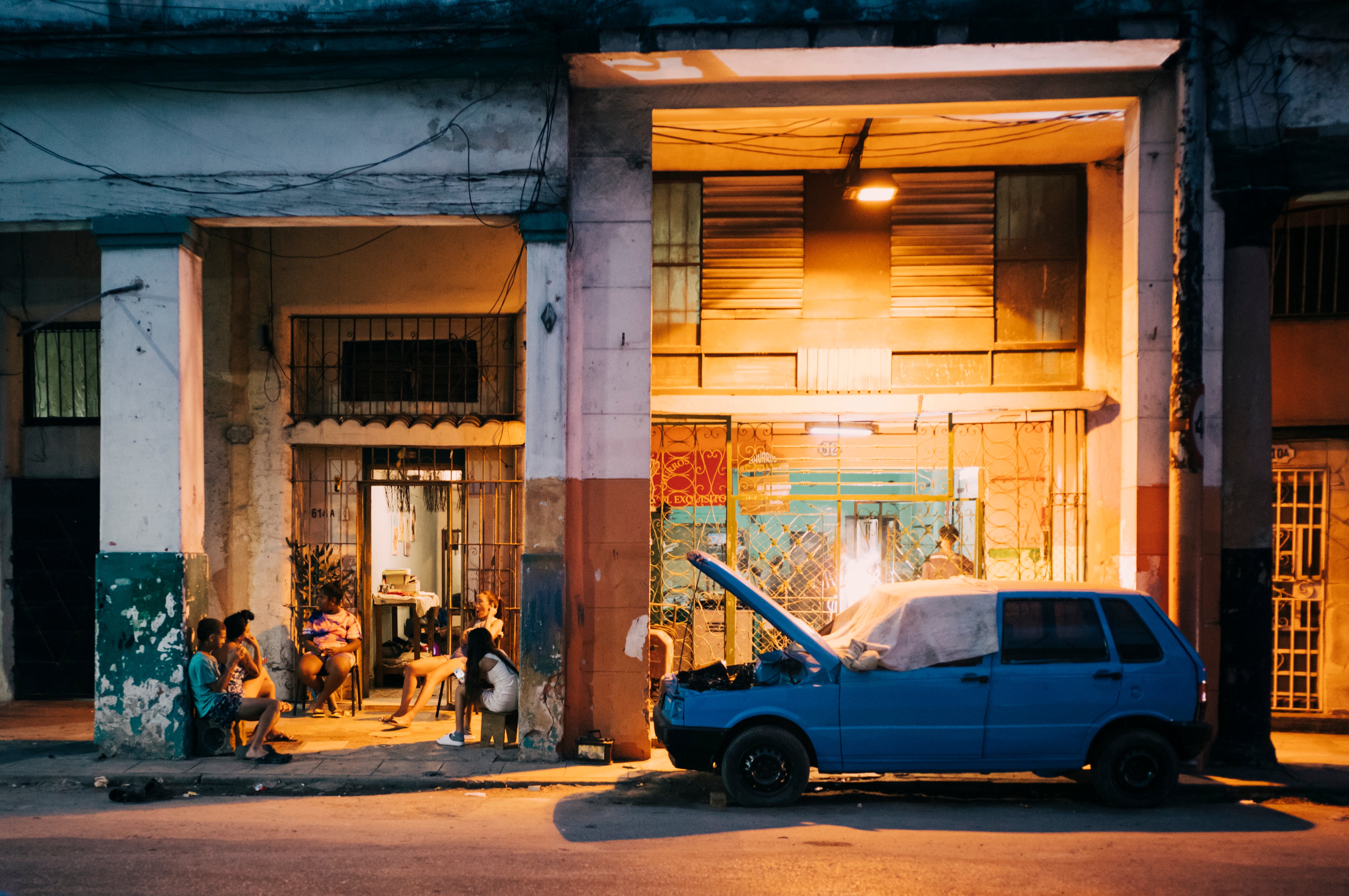 A family relaxes as a neighbour repairs his car in Havana