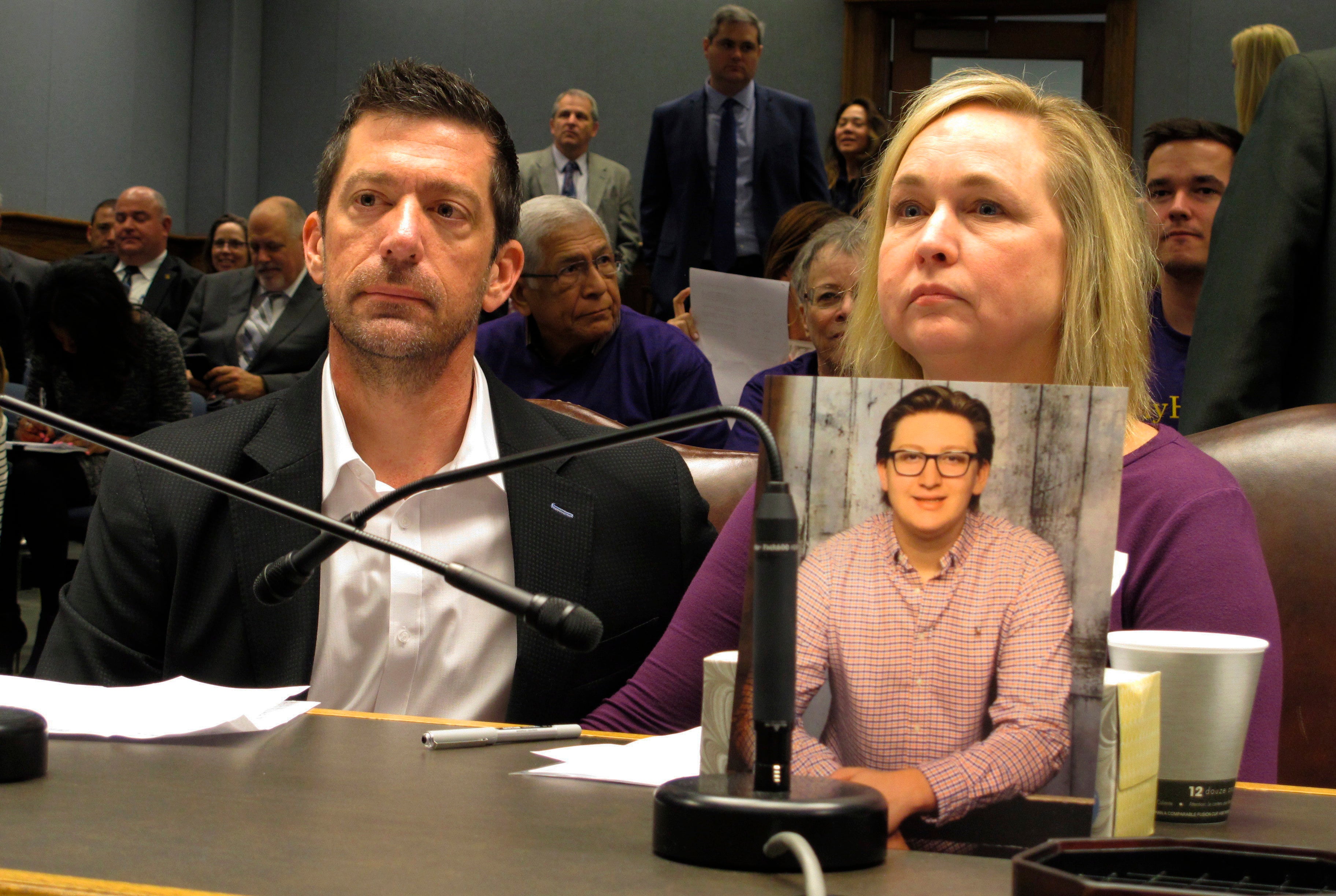 Stephen and Rae Ann Gruver with a photo of their son, Max, at a House committee room in Baton Rouge, Louisiana, in 2018