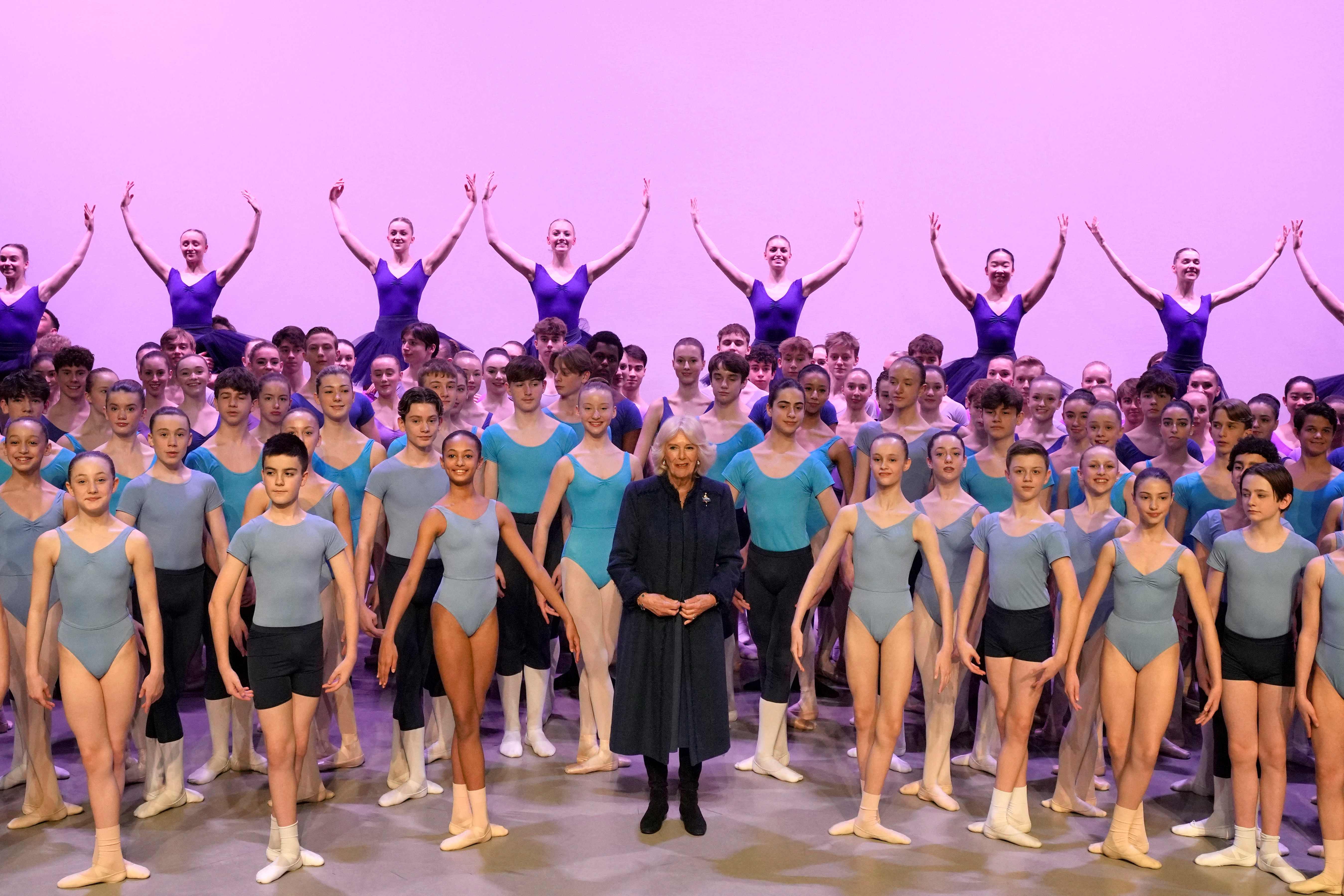 Camilla, Queen Consort (C) stands on stage with students during her visit to the Elmhurst Ballet School to celebrate the school's centenary