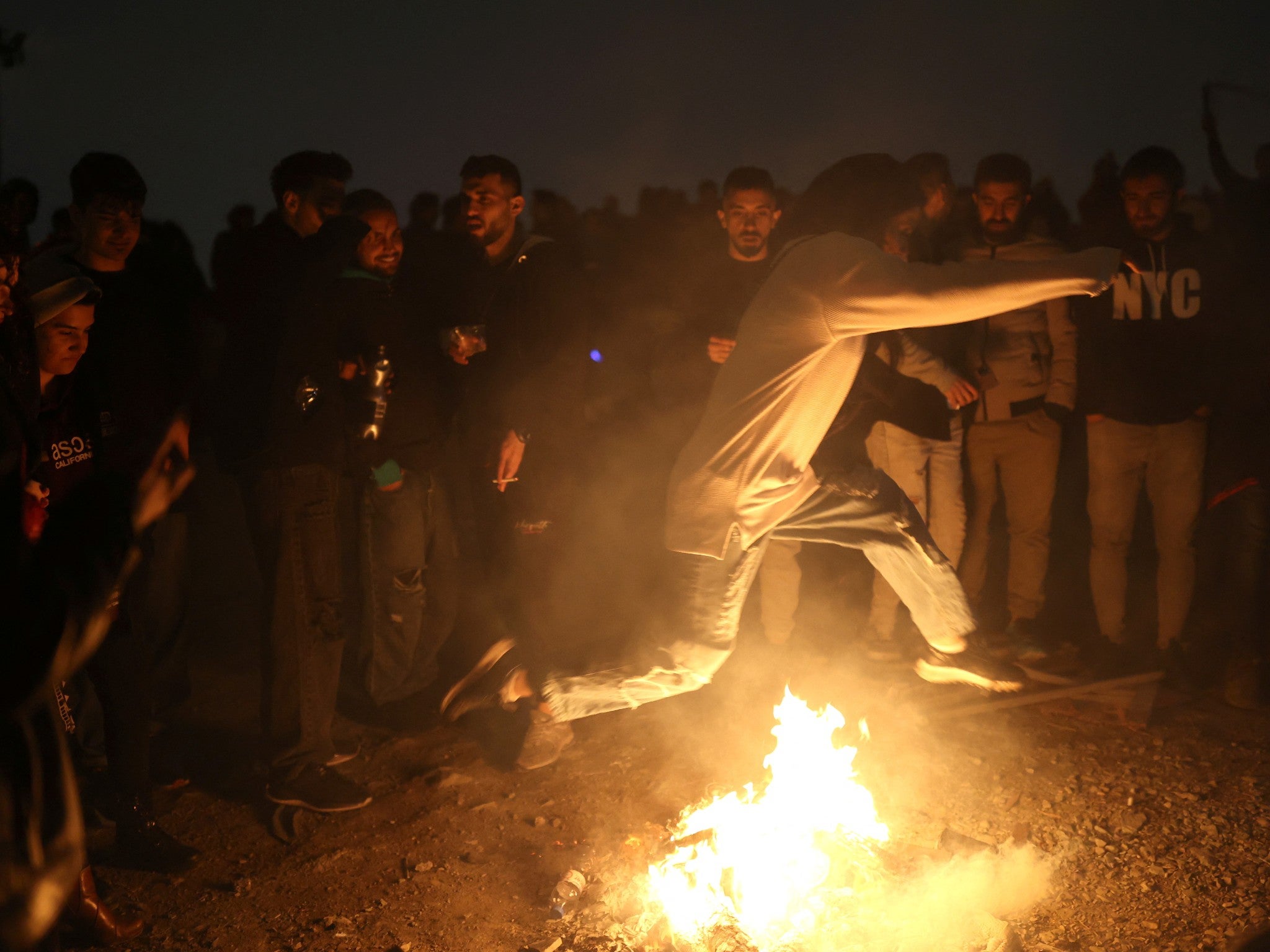 A woman leaps over fire during the traditional ‘Red Wednesday’ festival in a park in Tehran