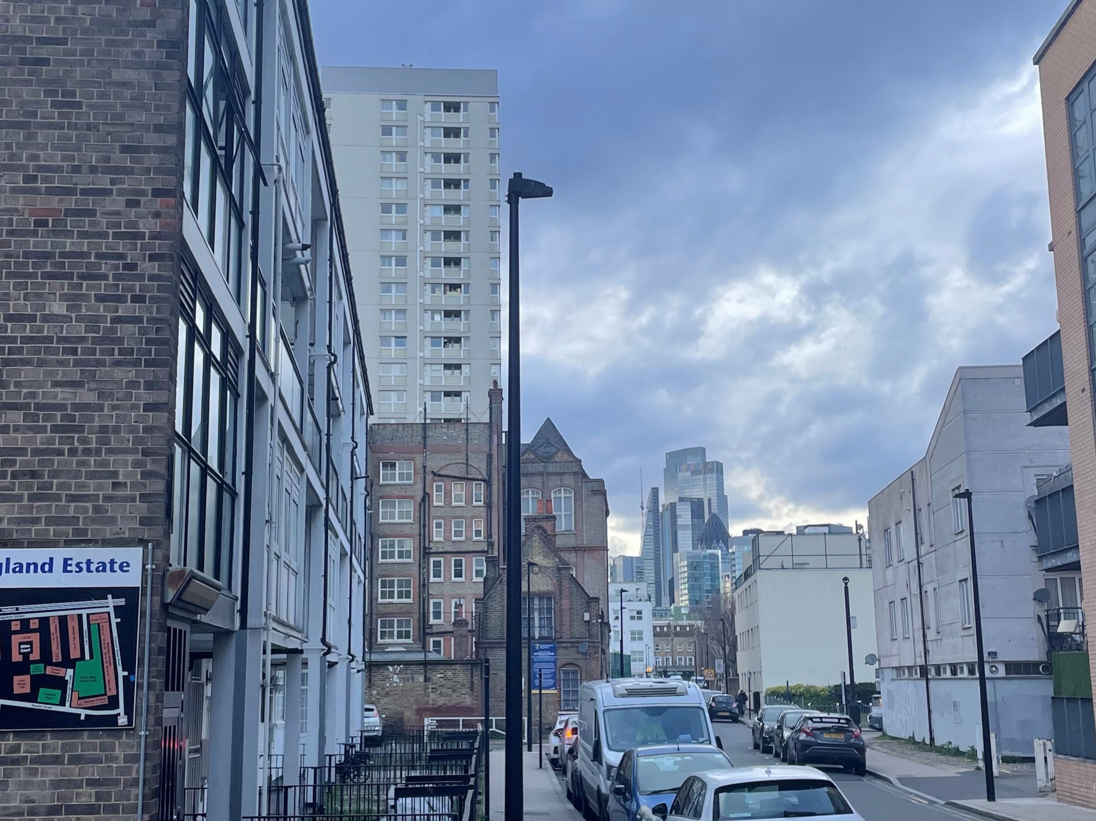 A sign for a housing estate in Shadwell, London, with the skycrapers of the financial district in the background