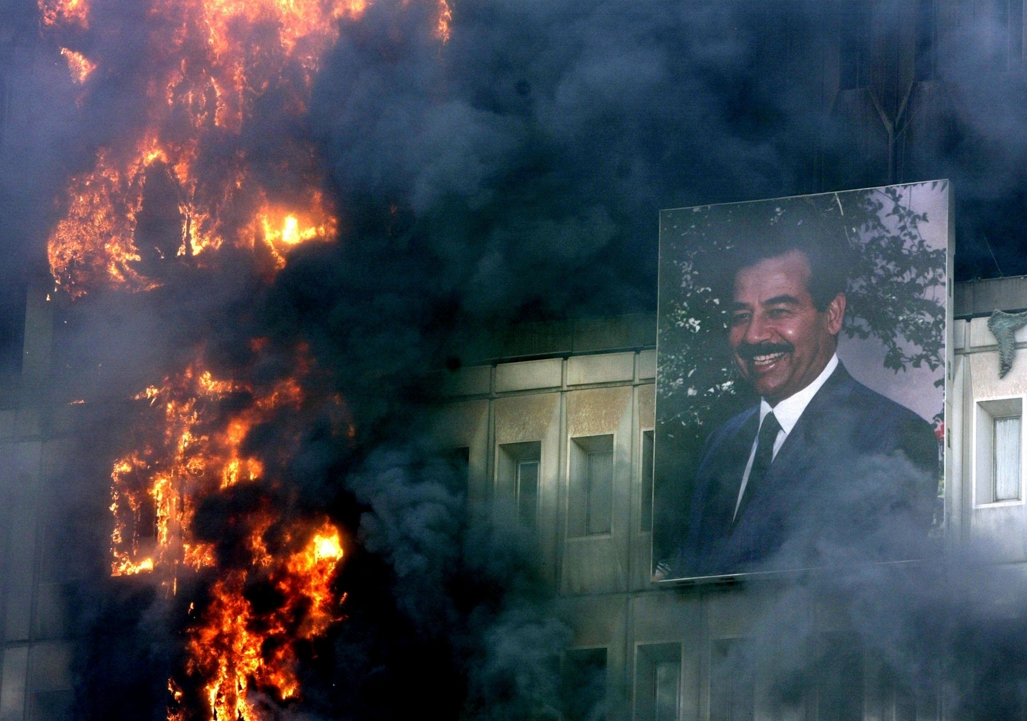 A portrait of Saddam Hussein hangs on the burning Ministry of Transport and Communication building in Baghdad, April 9, 2003