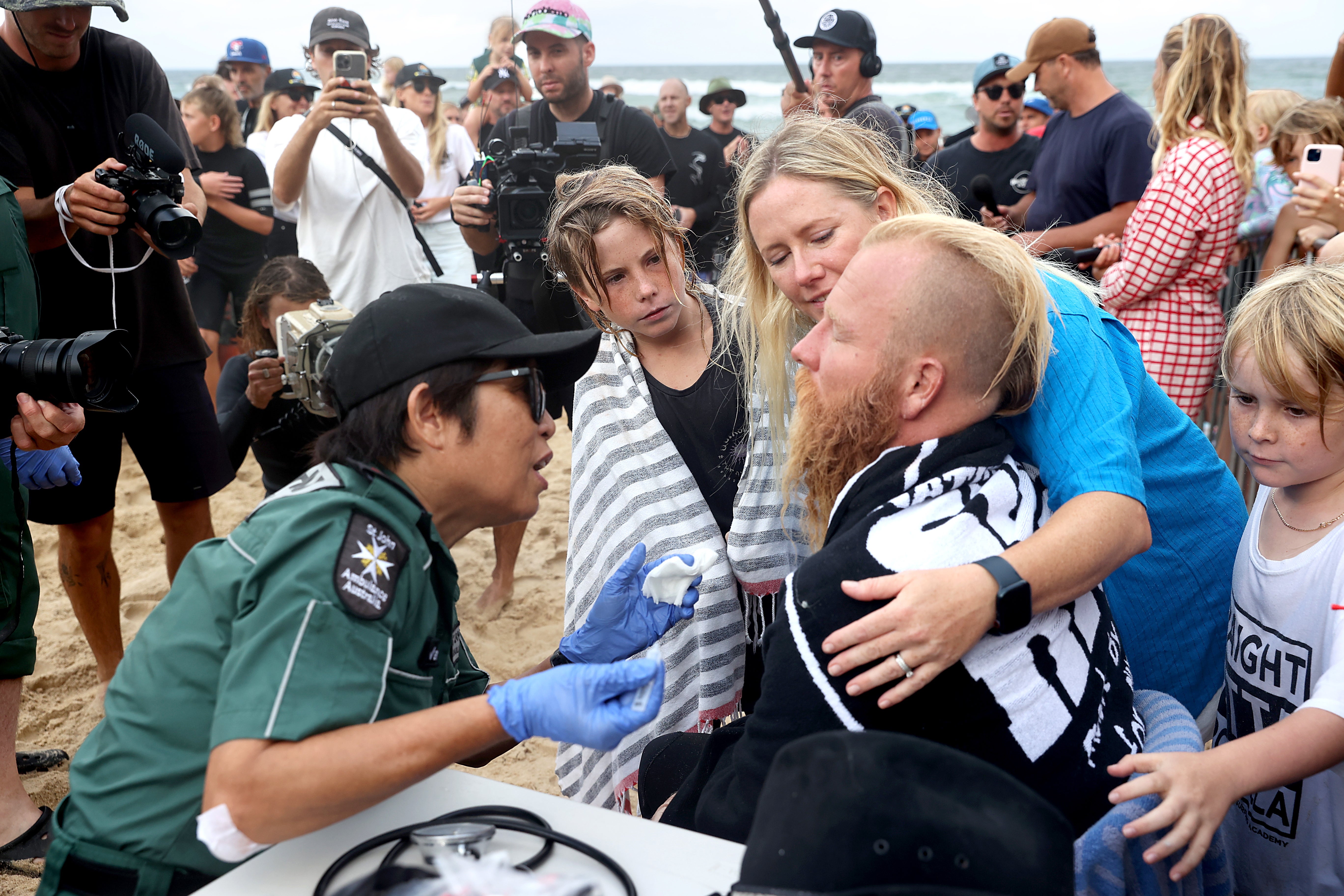 Australian surfer Blake Johnston is checked by medics as his family watches on after achieving a new world record for the longest surf session of 500 waves in over 30 hours, at The Alley in Cronulla, in Sydney, Australia, 17 March 2023