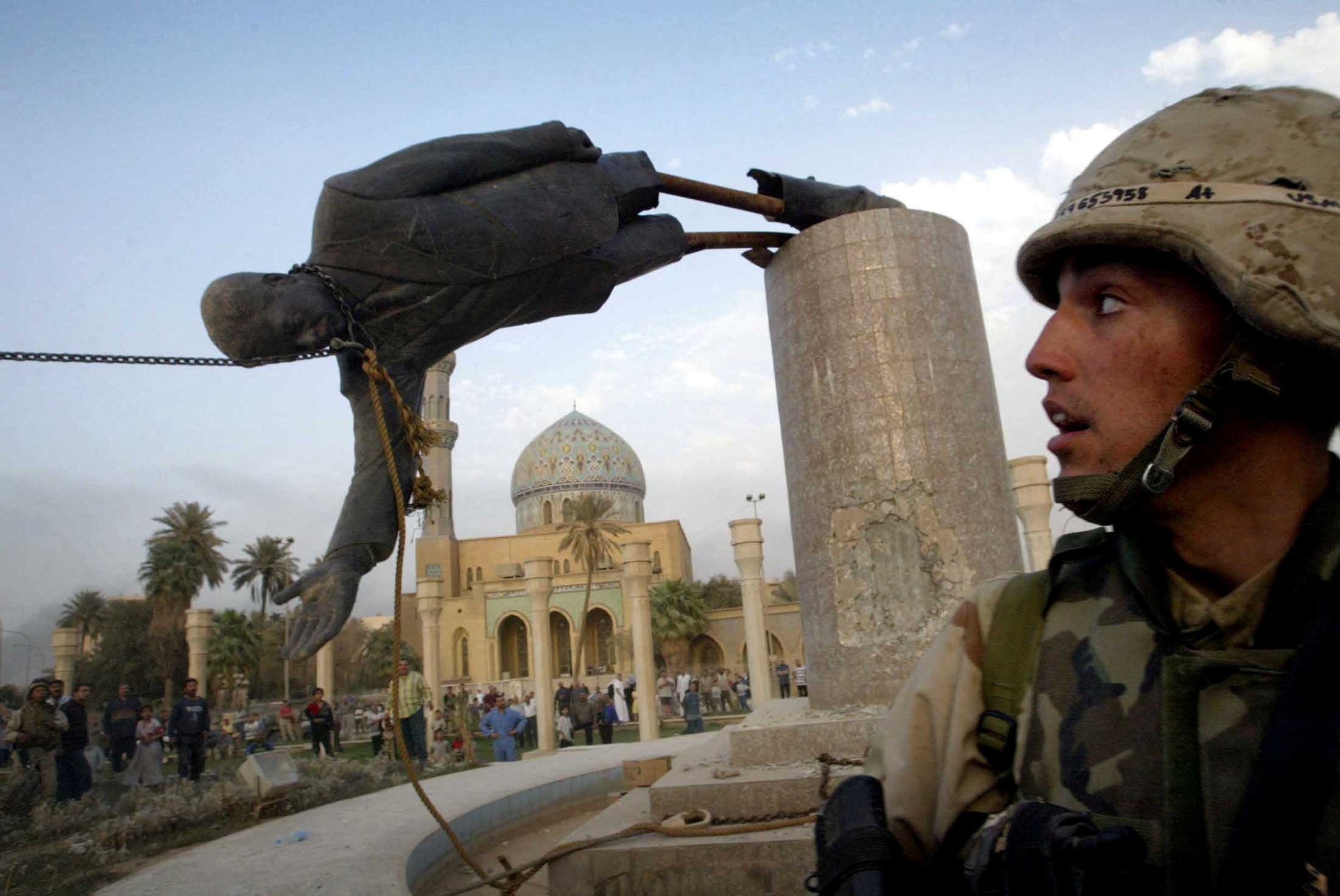 A US marine watches as the statue of Saddam Hussein falls in central Baghdad's Firdaus Square, 9 April, 2003