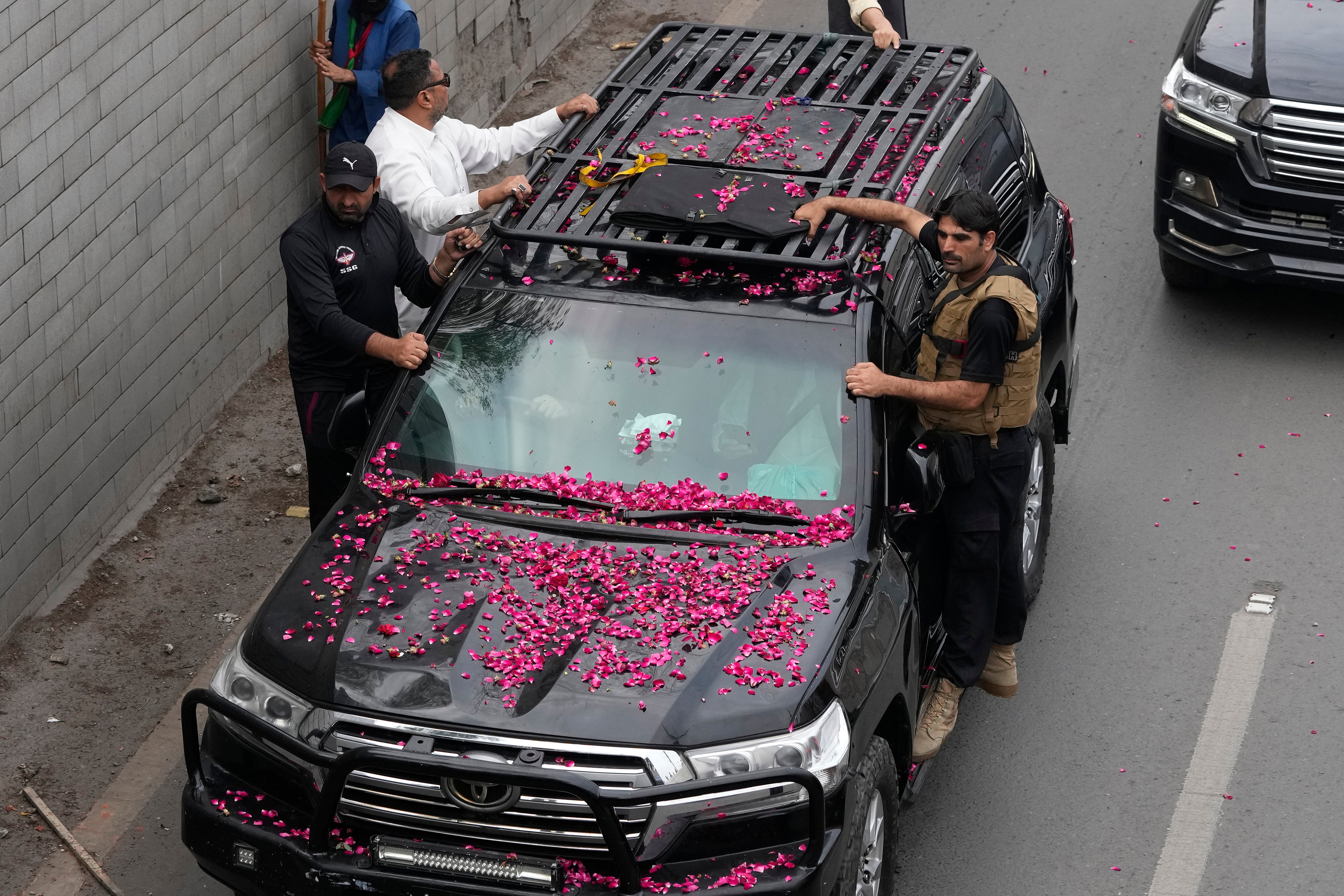 Security personnel climb on a vehicle carrying former prime minister Imran Khan as it moves toward Islamabad at a road in Lahore, Pakistan, 18 March 2023