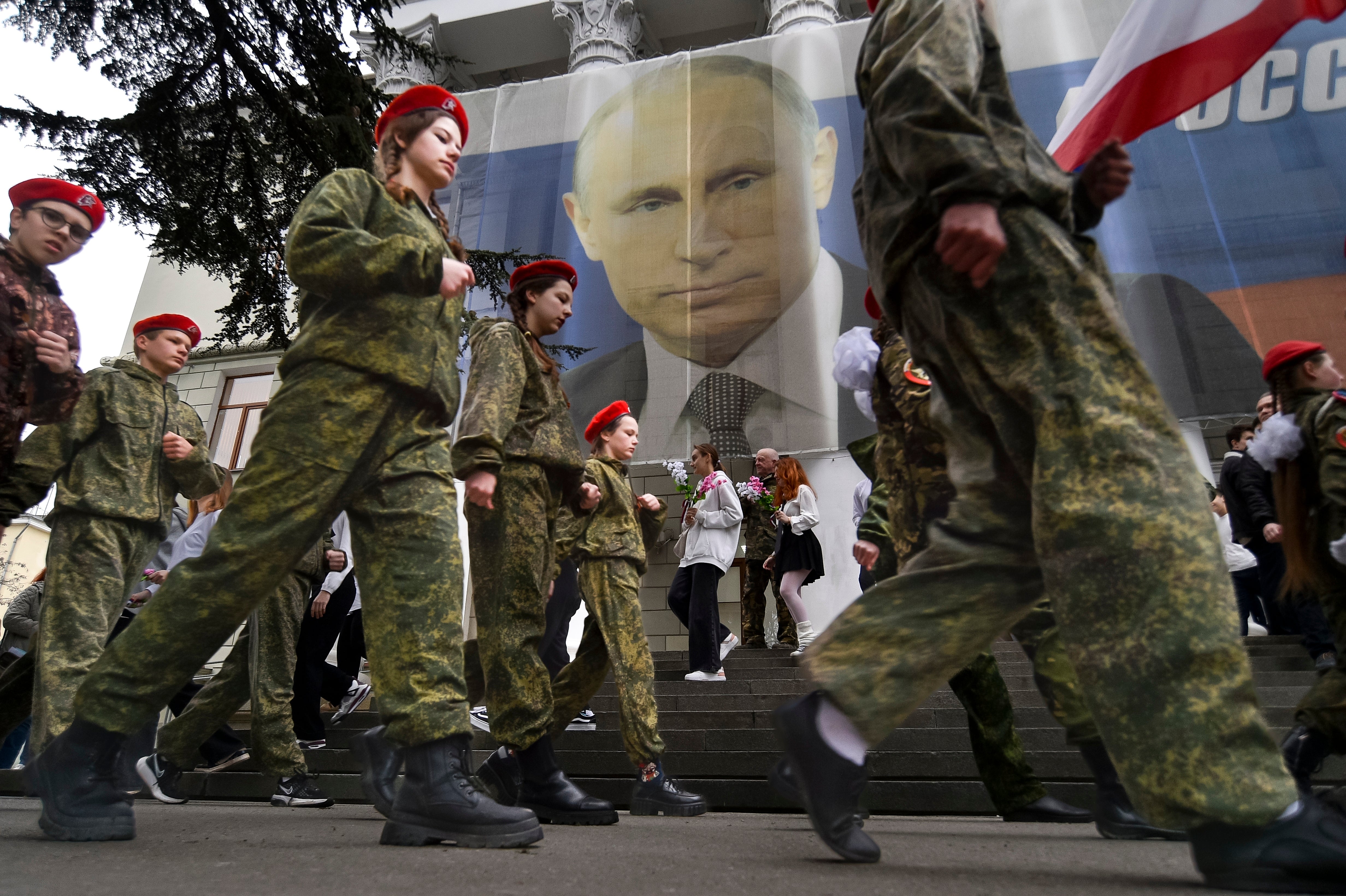 Youths parade to mark the ninth anniversary of the Crimea annexation with a banner reading: “Russia doesn’t start wars, it ends them” ahead of Putin’s visit, in Yalta, Crimea