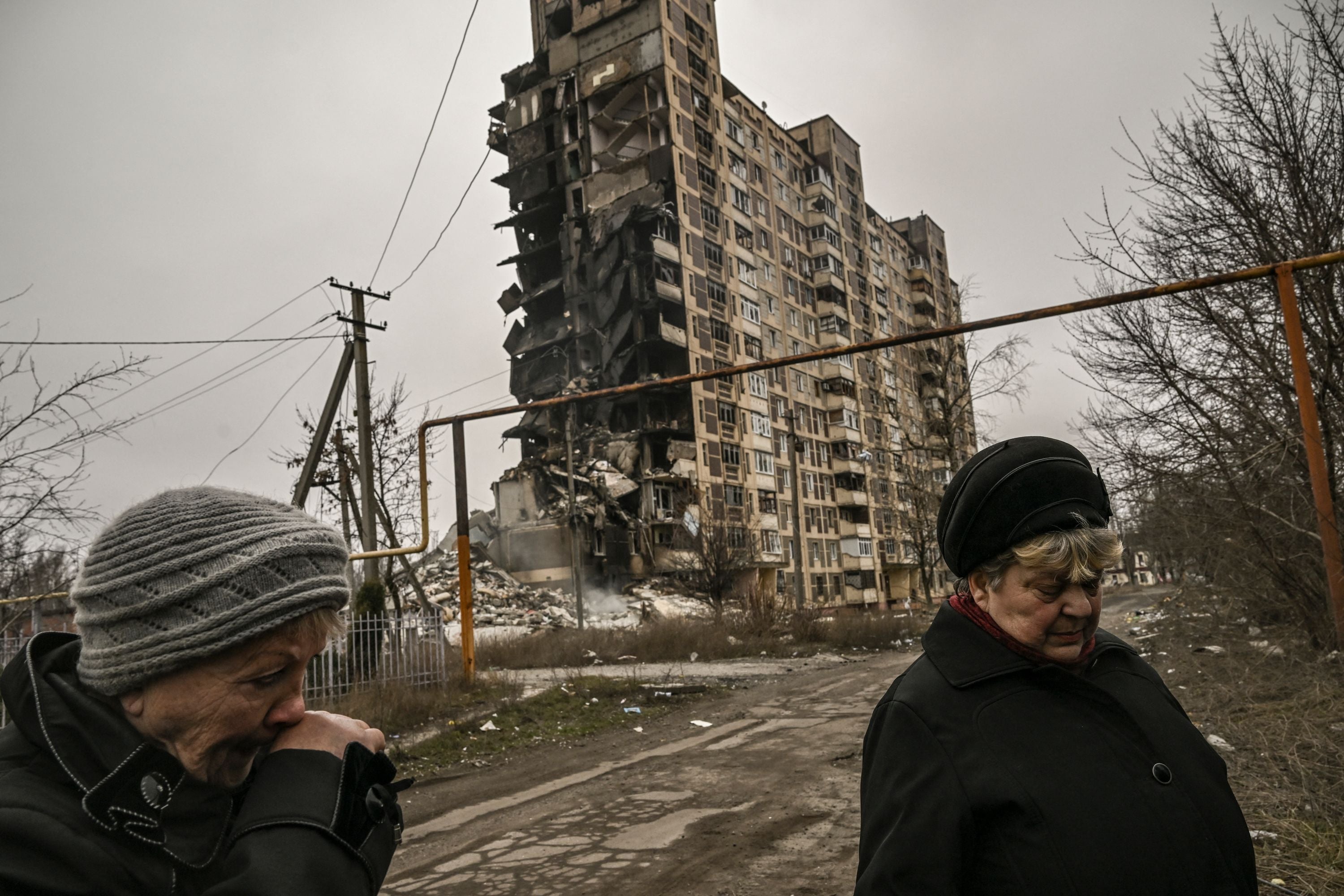 Two eldery women stand in front of a destroyed apartment building after a strike, in the city of Avdiivka, Donetsk