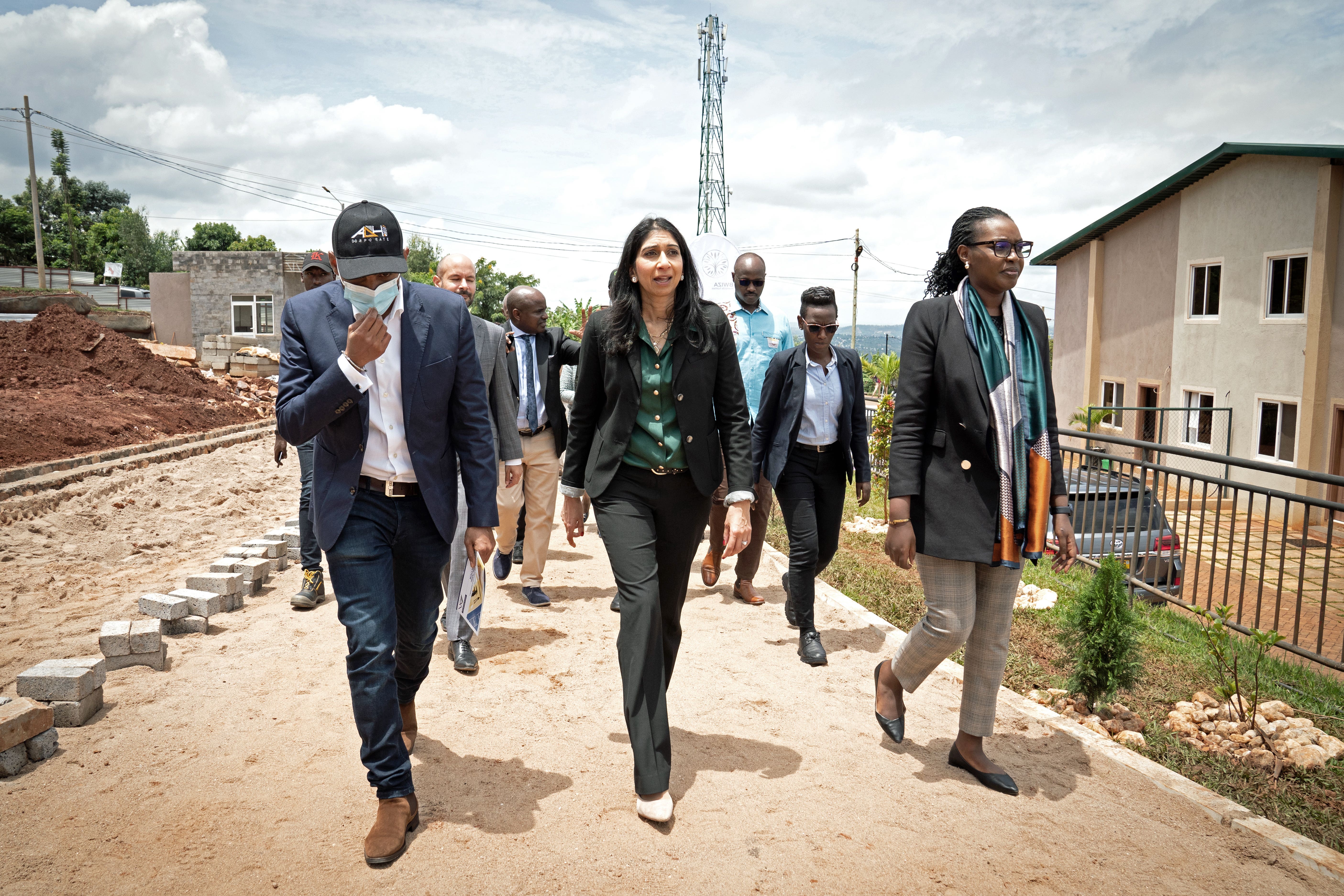 Suella Braverman, centre, tours a building site on the outskirts of Kigali