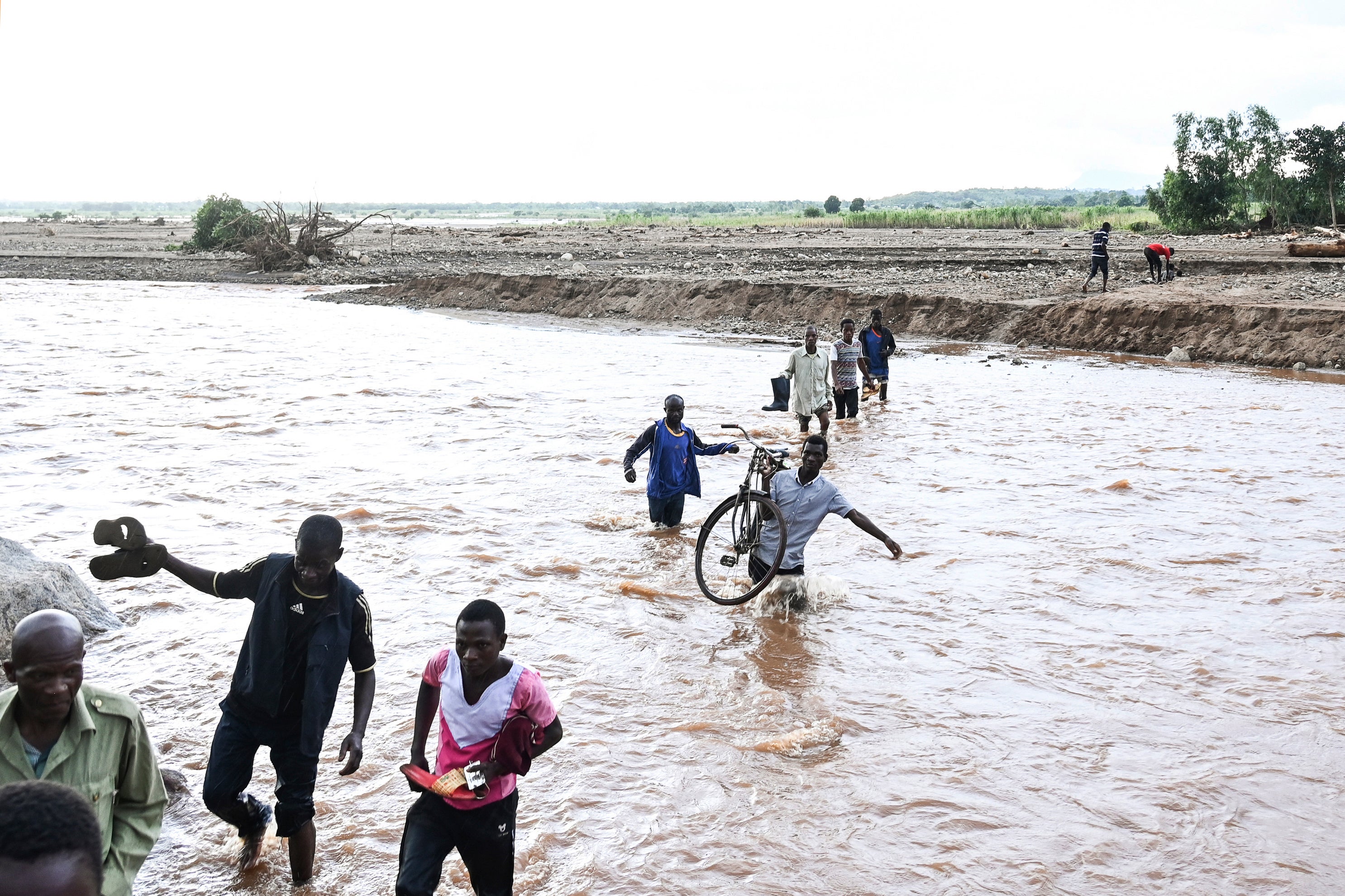 People wade through flood waters caused by last week’s heavy rains caused by Tropical Cyclone Freddy in Phalombe, southern Malaw