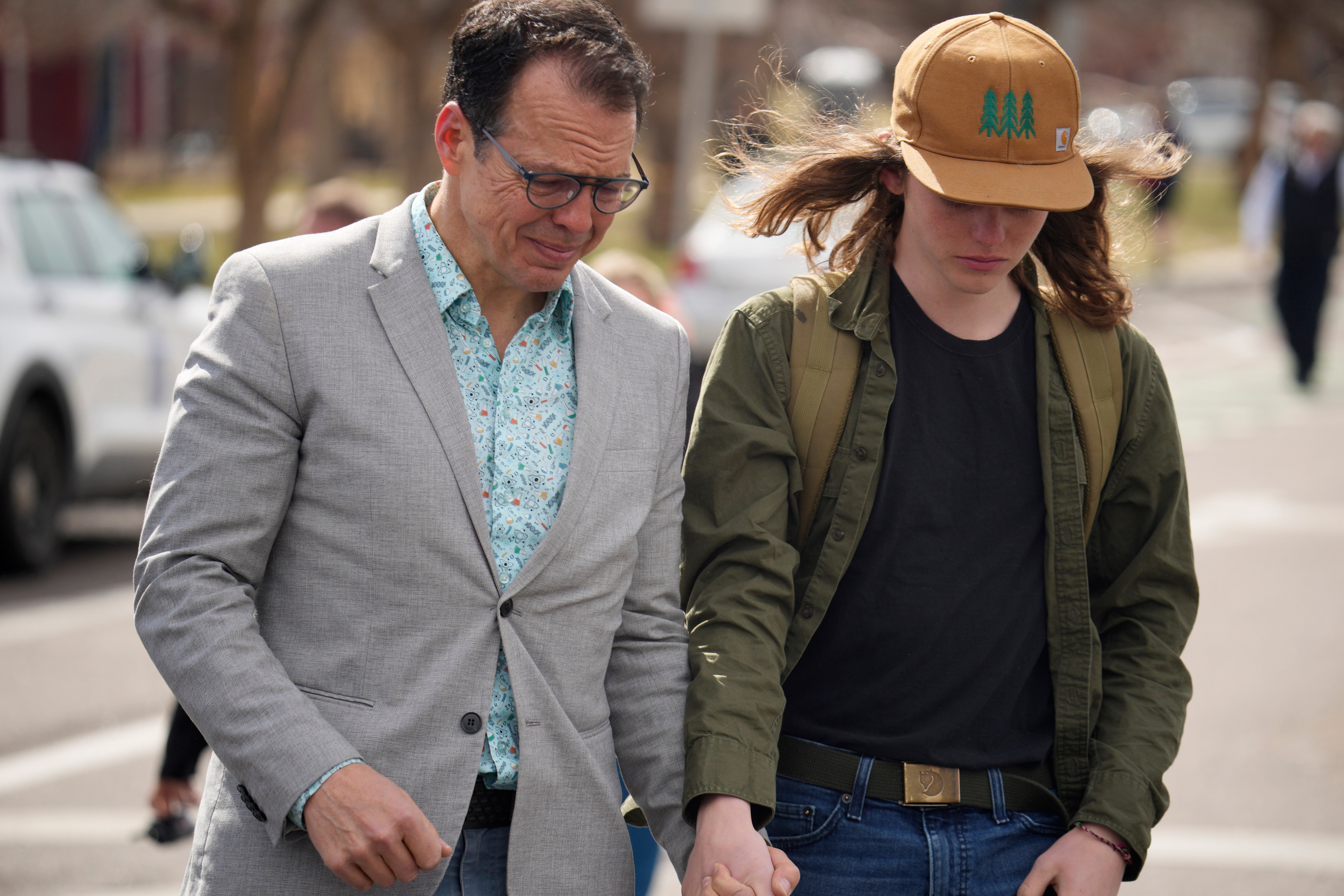 A man holds hands with a student following their reunion after a school shooting at East High School Wednesday, March 22, 2023, in Denver