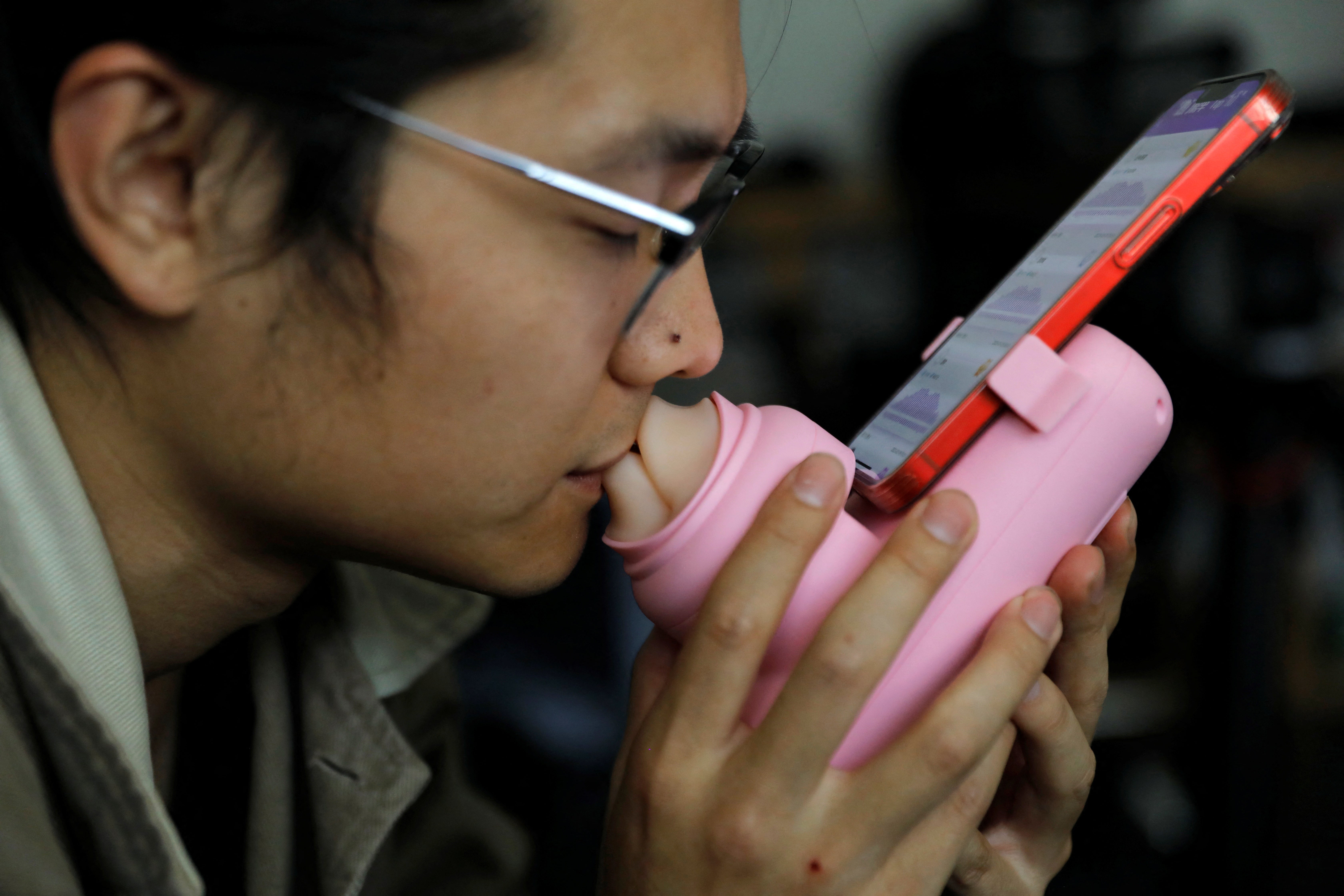 Jing Zhiyuan uses a remote kissing device ‘Long Lost Touch’, as he demonstrates for camera how to use it