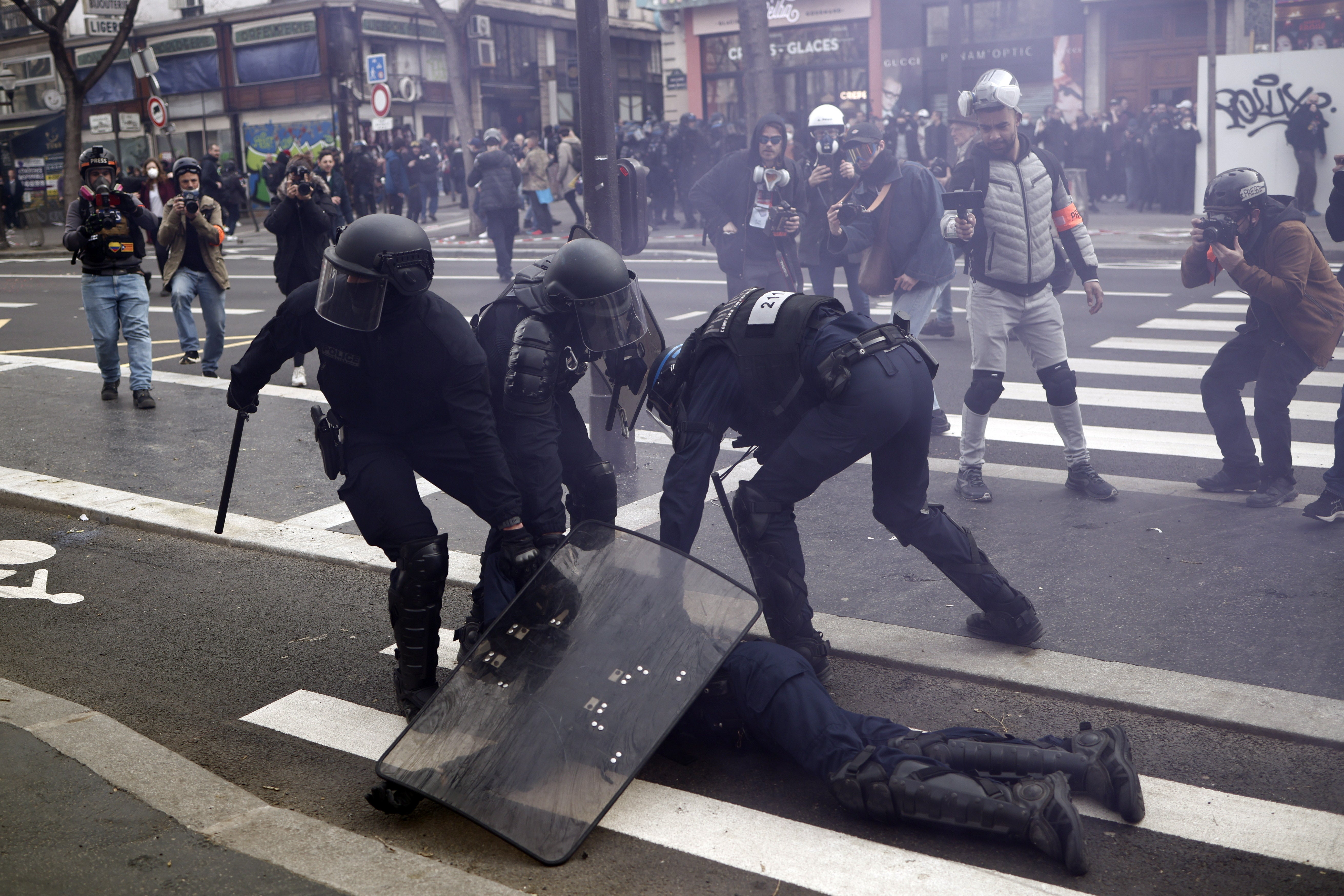 French police officers protect a colleague injured during clashes with protesters