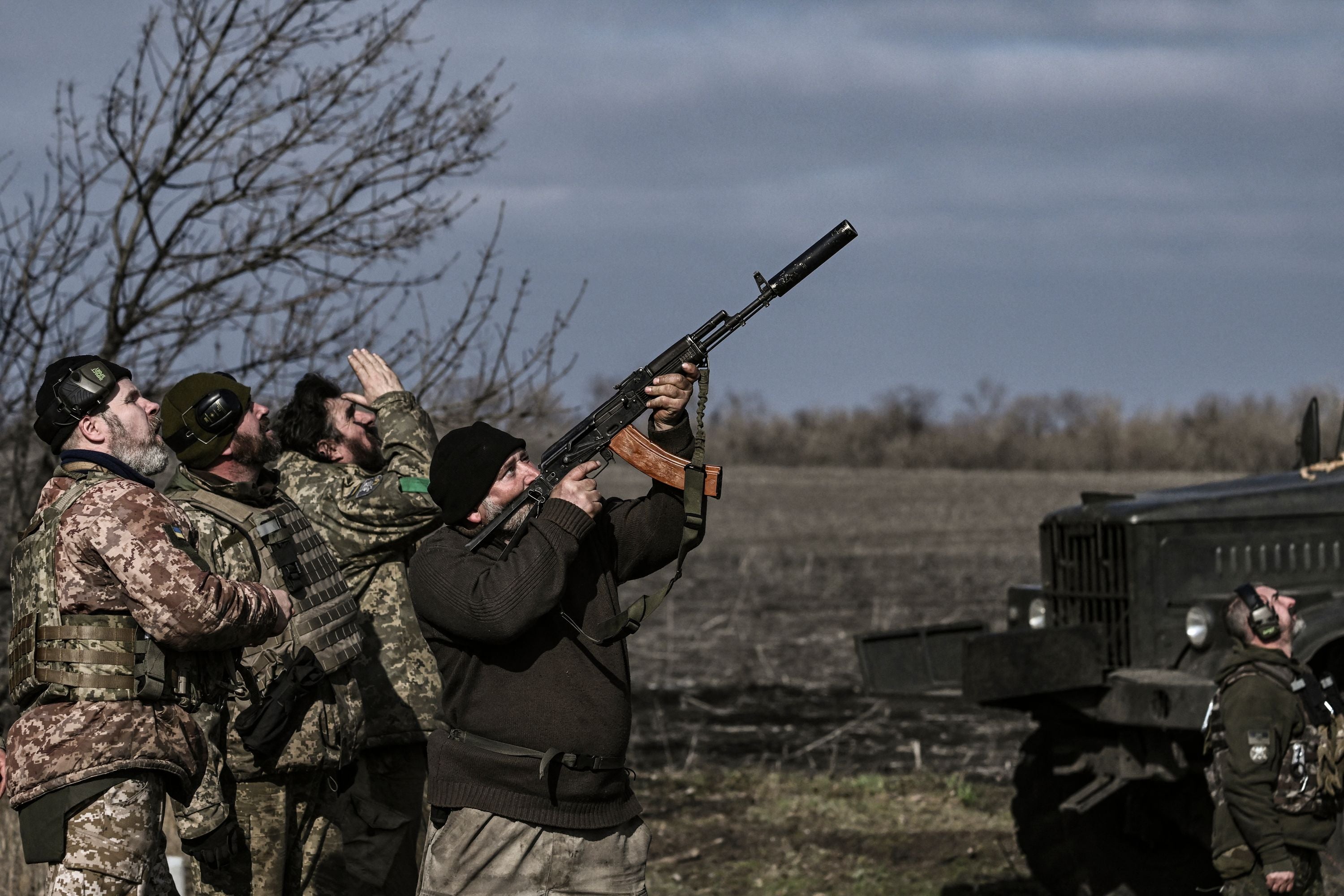 A Ukrainian serviceman fires his rifle at a drone flying above their position near Bakhmut