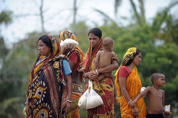 Indian villagers collect donated food from a social work organisation in the cyclone-hit village of Kumirmari in the Sundarbans in 2009