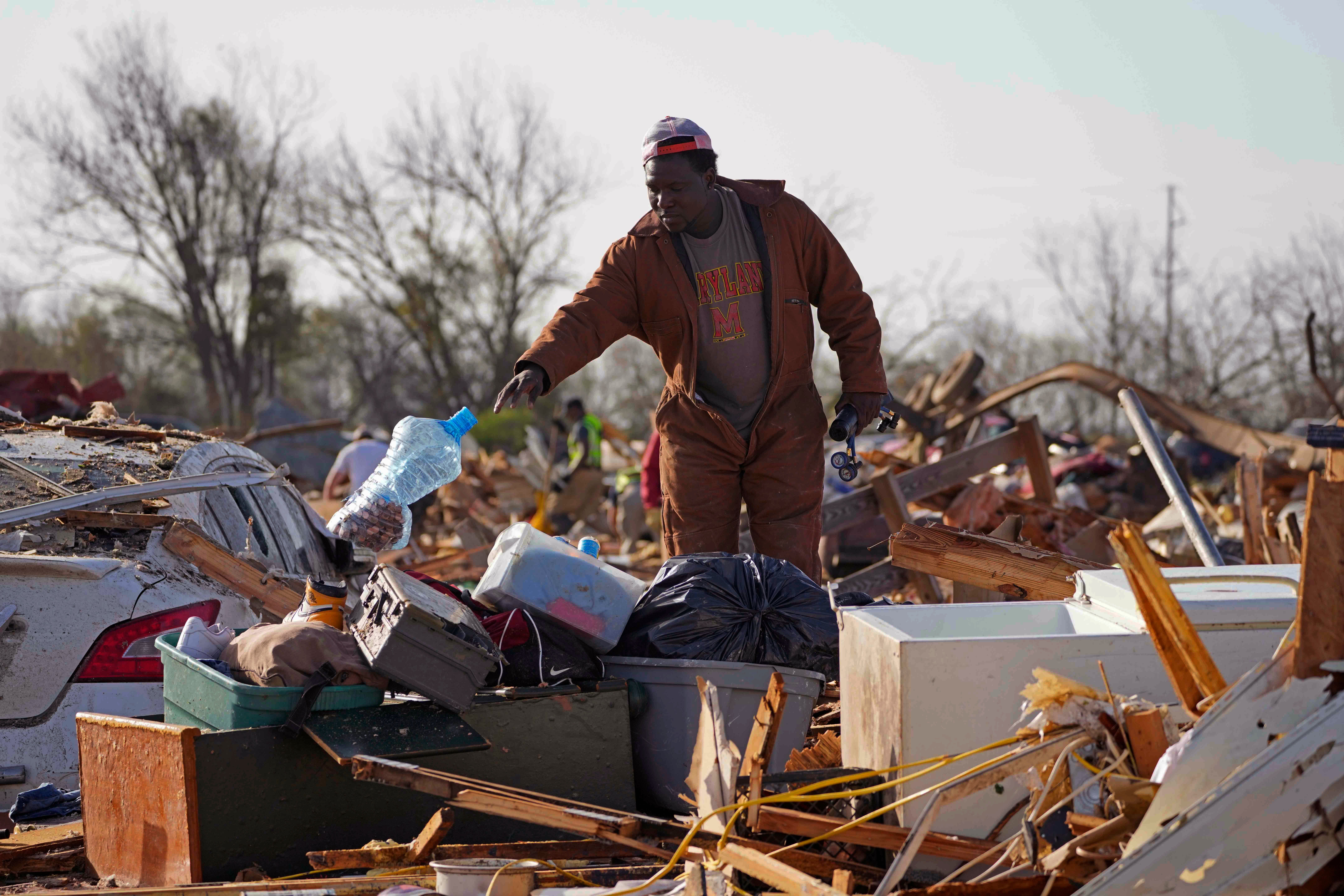 A resident looks through the piles of debris, insulation, and home furnishings to see if anything is salvageable at a mobile home park in Rolling Fork