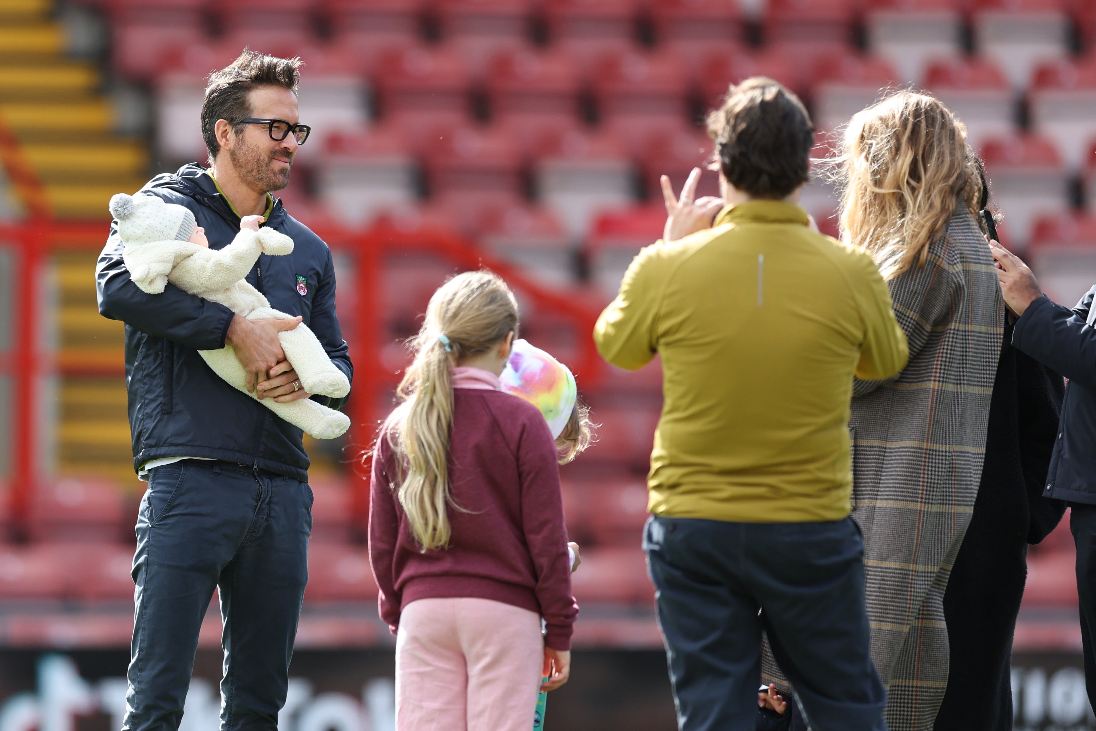 Wrexham co-owner Ryan Reynolds has pictures of himself with his children on the pitch at The Racecourse Ground, Wrexham prior to the Vanarama National League match between Wrexham and York City at the Racecourse Ground on March 25, 2023 in Wrexham