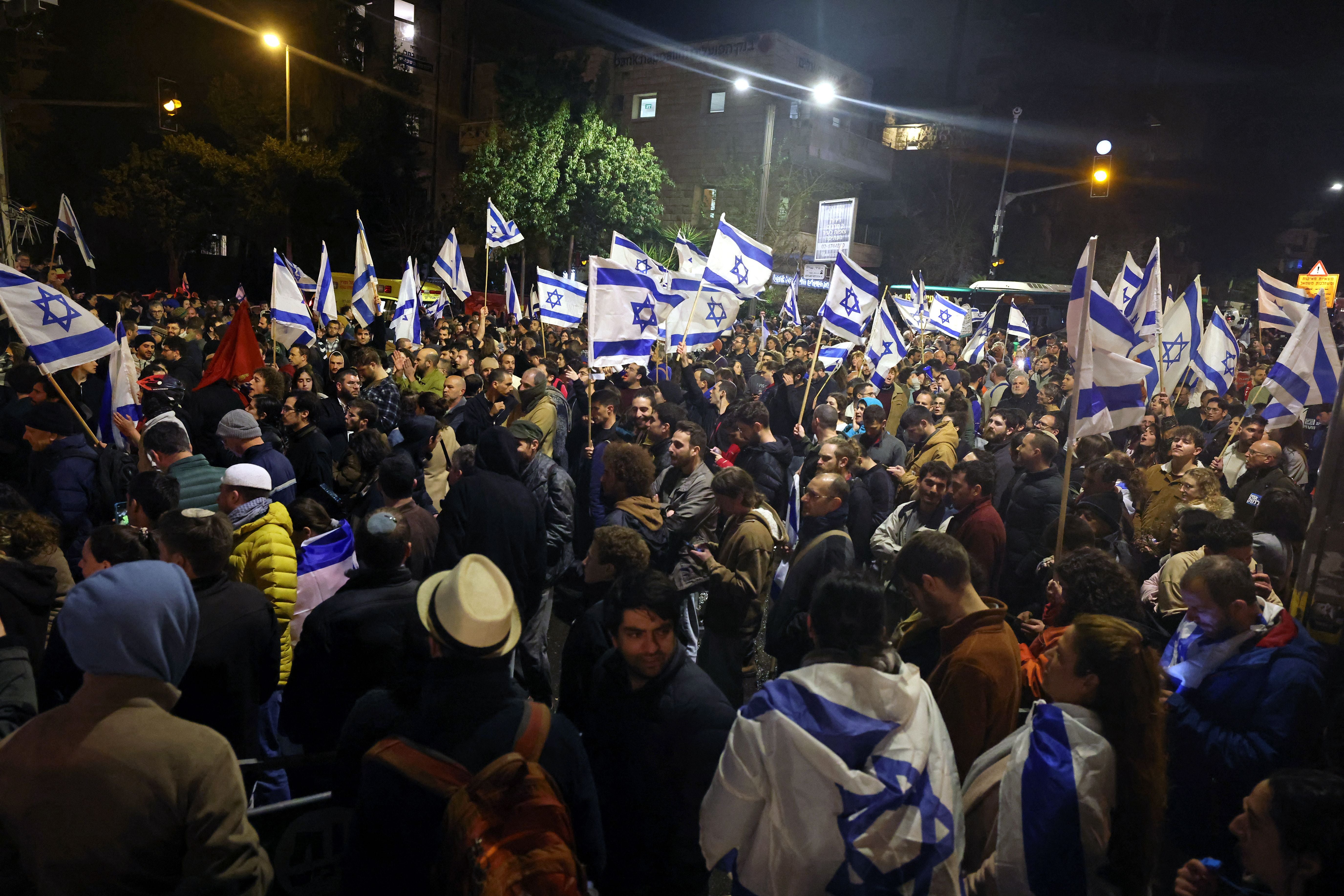 Demonstrators wave national flags during a rally against the Israeli government's judicial reforms outside Prime Minister Benjamin Netanyahu's residence in Jerusalem