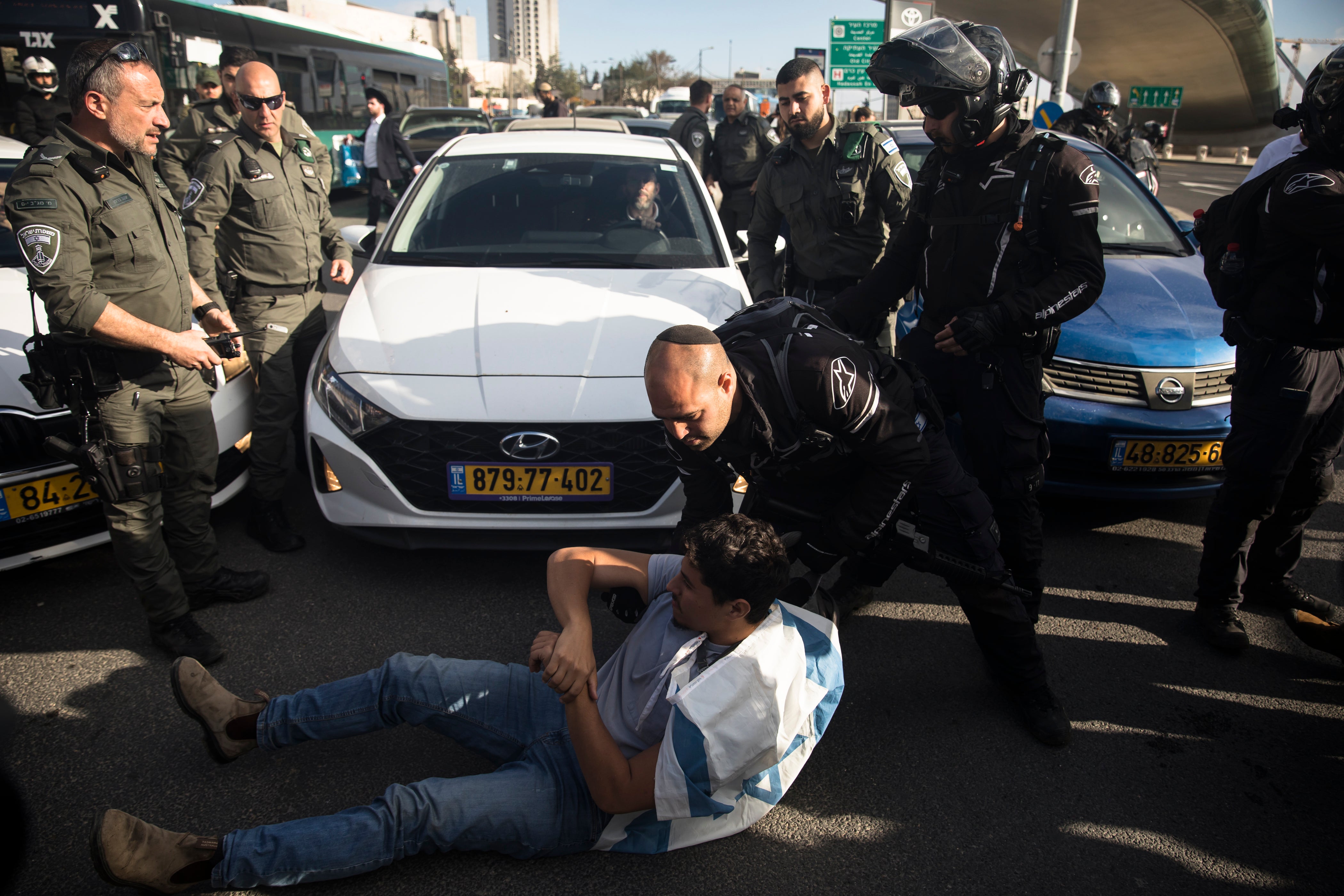 Israeli police officers remove a protester blocking a main road