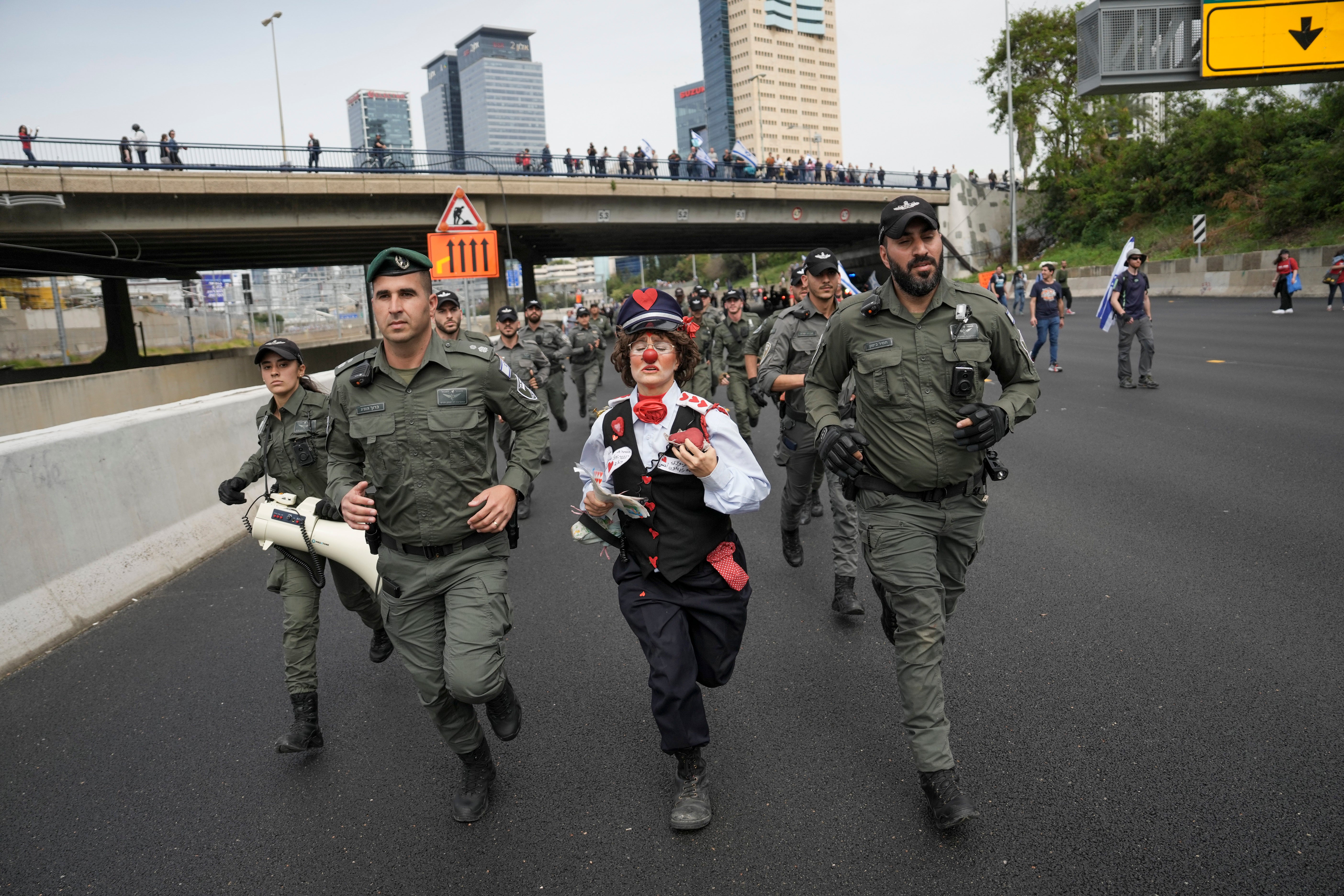 An Israeli activist dressed as a clown runs with border police