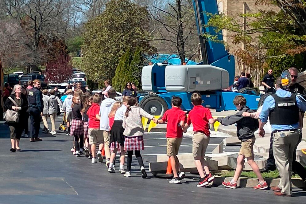 Children from The Covenant School, a private Christian school in Nashville, Tenn., hold hands as they are taken to a reunification site at the Woodmont Baptist Church after a shooting at their school