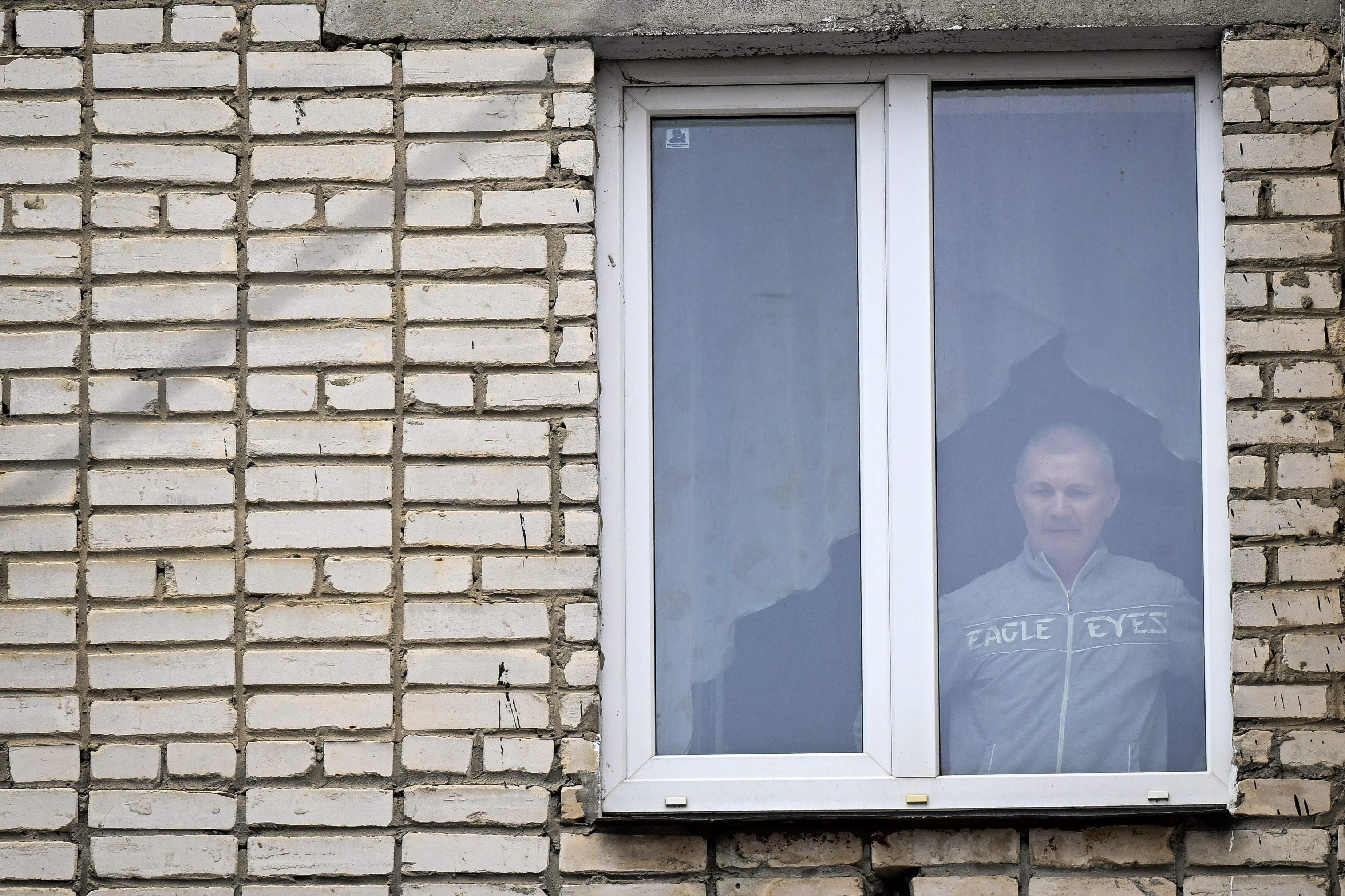 Alexei Moskalyov, 54, a single parent of Maria Moskalyova, the 13-year-old girl who drew a picture critical of Moscow's military campaign in Ukraine at school in April last year, looks out through the window of his flat after he was placed under house for repeating Ukraine posts discrediting the Russian army