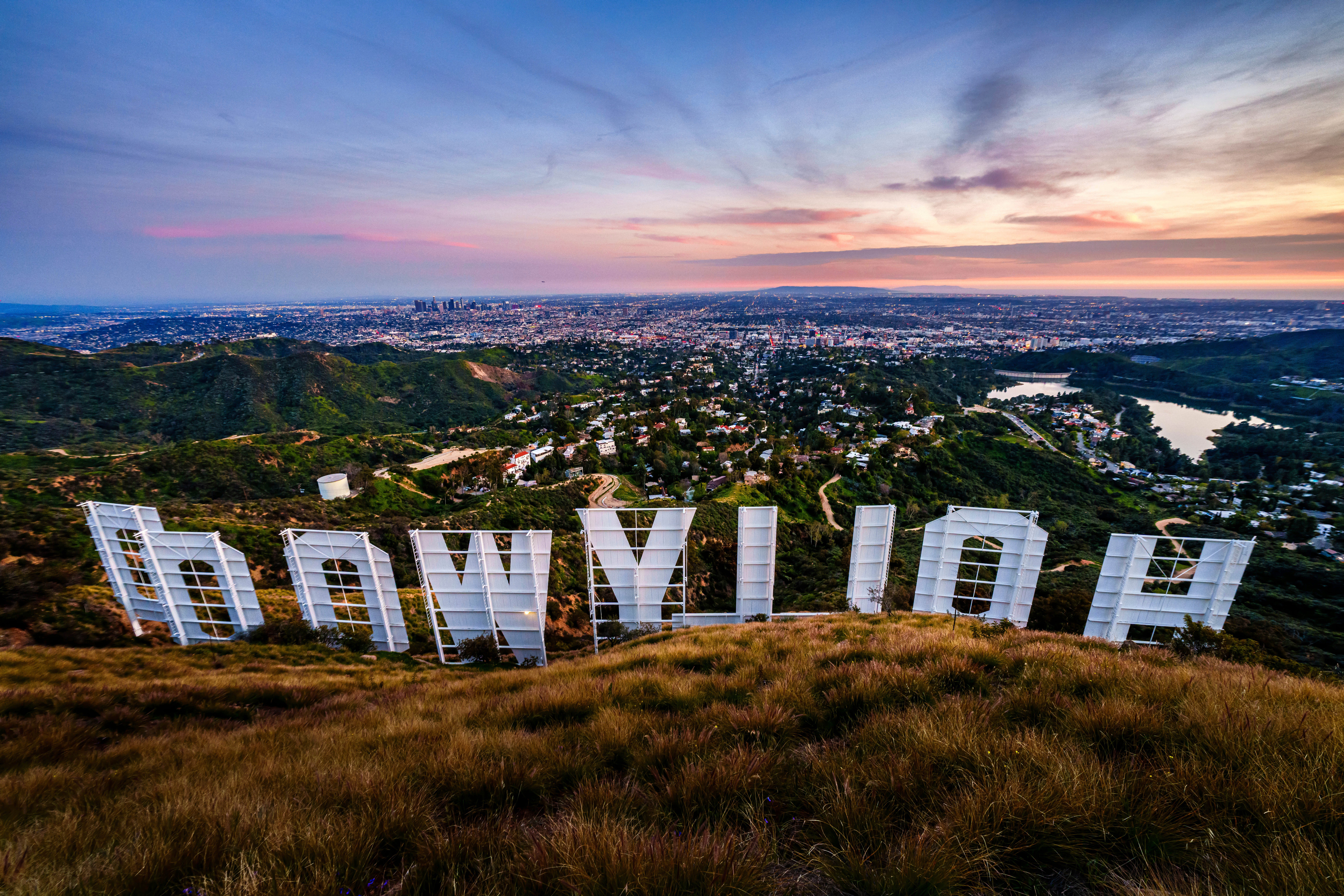 Sunset casts a pink glow over the Los Angeles skyline as seen from behind the famous Hollywood sign Wednesday evening, March 8, 2023