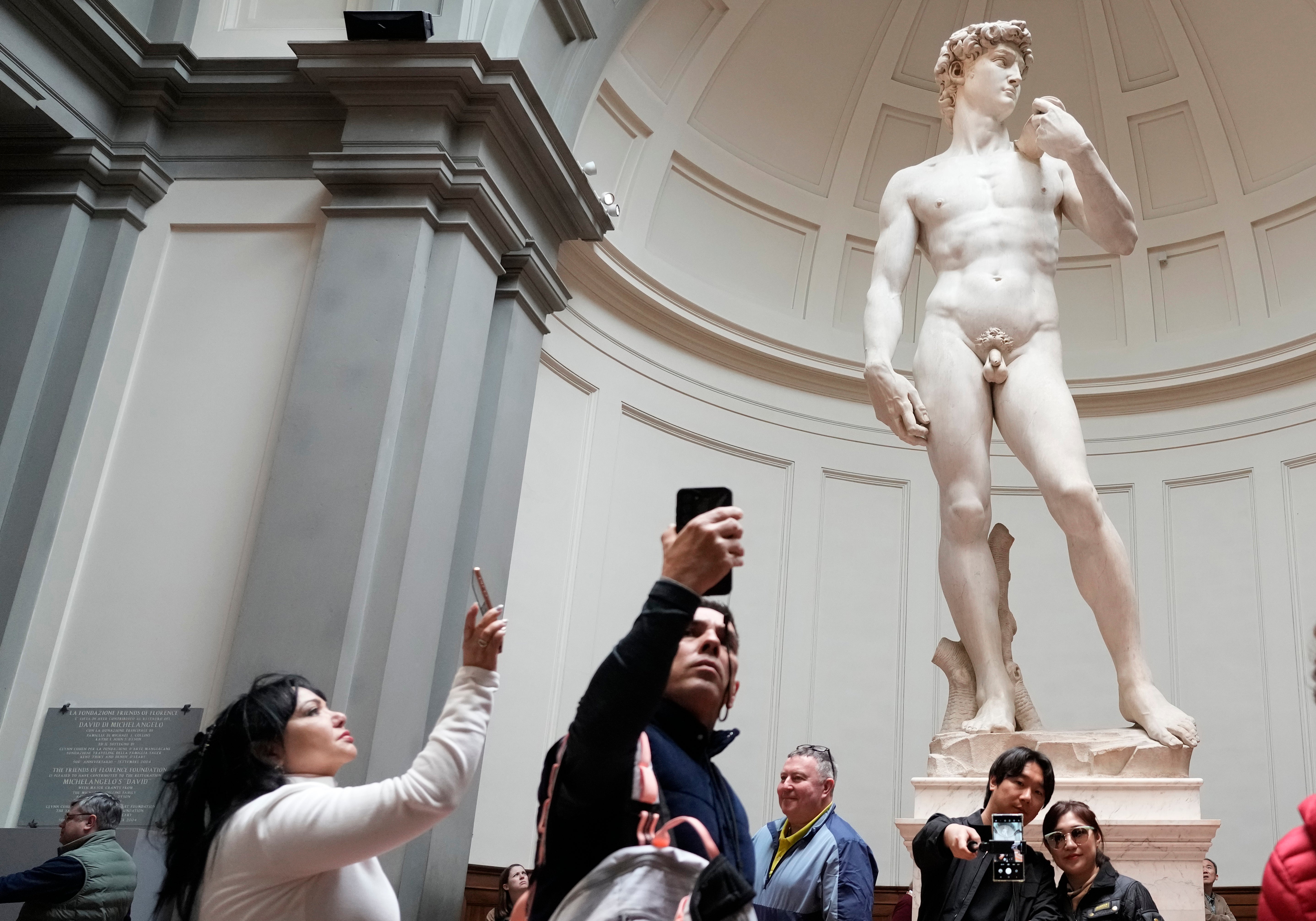 Tourists take photos in front of Michelangelo’s David statue in the Accademia Gallery in Florence, Italy