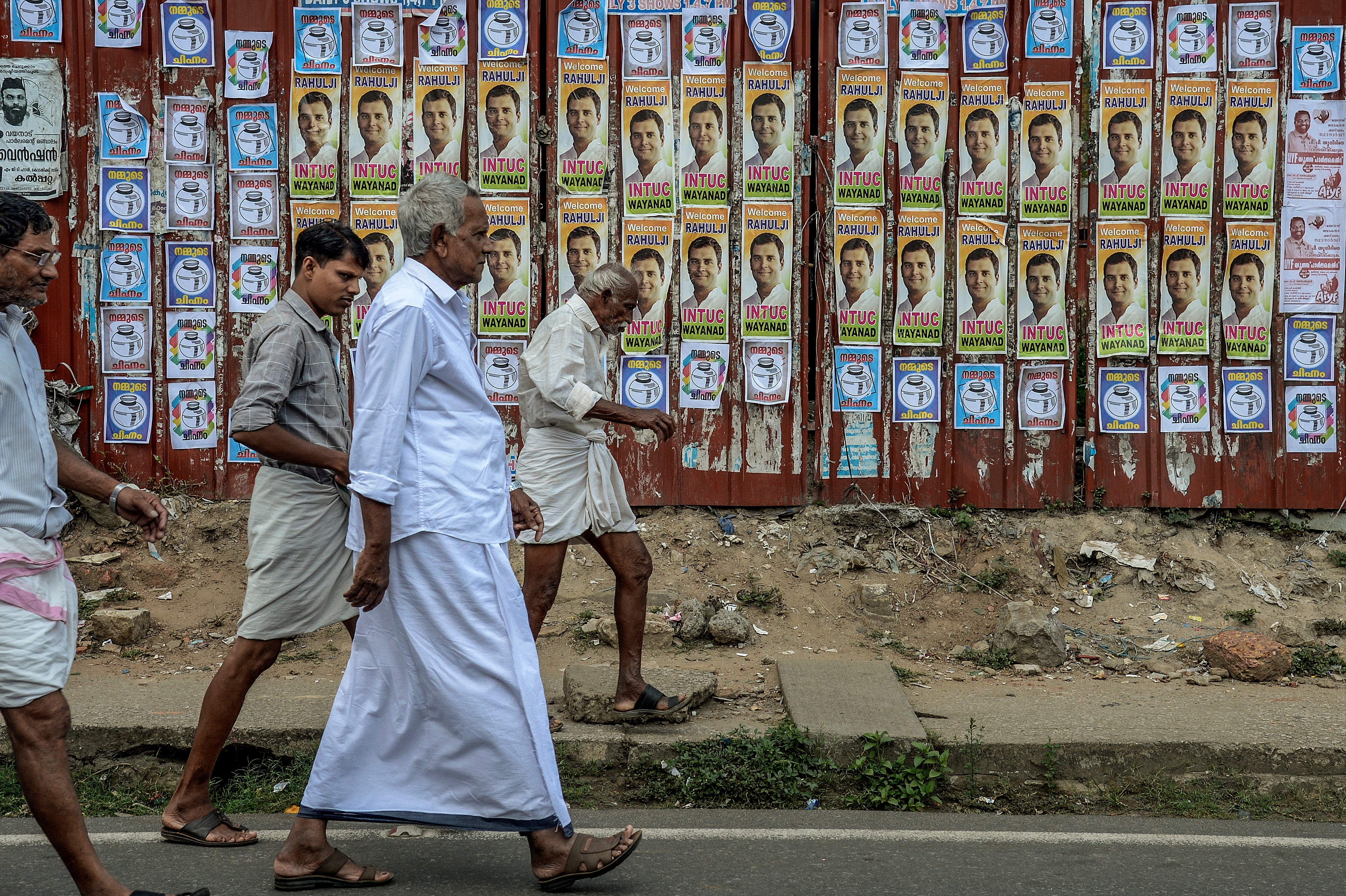 File: Congress party supporters walk in front of posters of Rahul Gandhi after he files nominations from Wayanad district on April 4, 2019