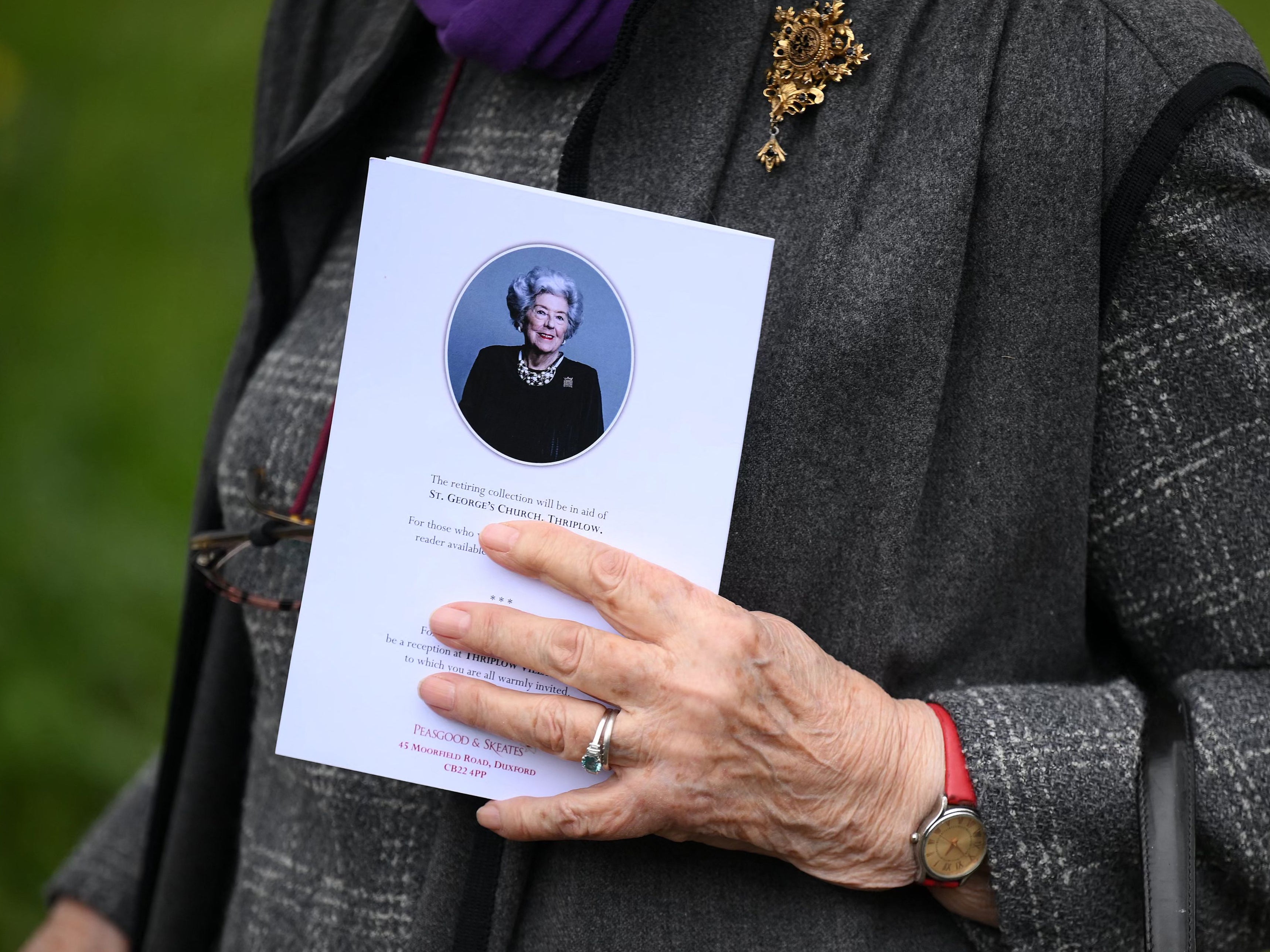 A mourner carries an order of service