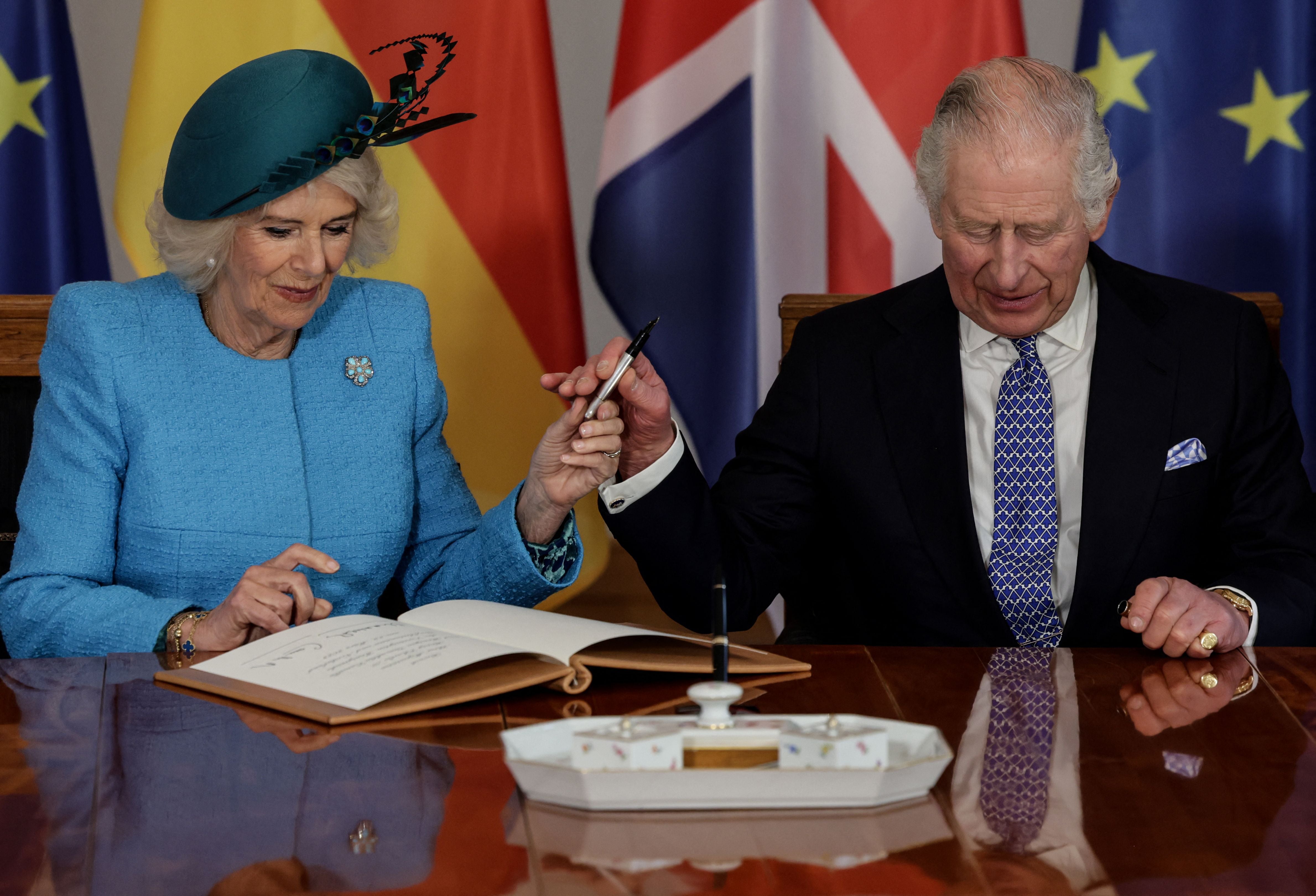 Charles hands over a pen to Camilla to sign the guest book at the presidential Bellevue Palace in Berlin