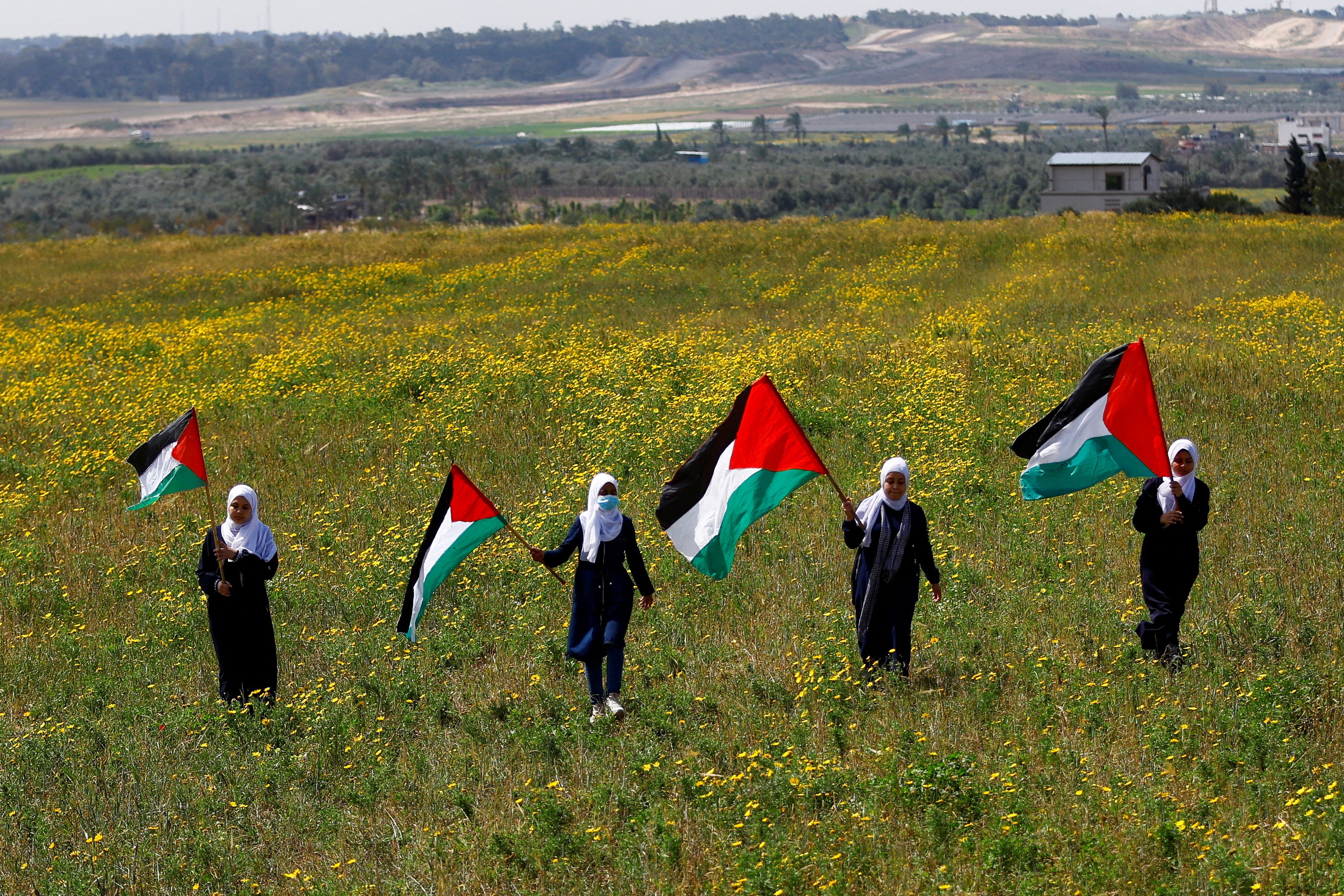 Palestinians hold flags as they mark 'Land Day', an annual commemoration of six Arab citizens of Israel who were killed by Israeli security forces during demonstrations over land confiscations in 1976, in the southeast of Gaza City