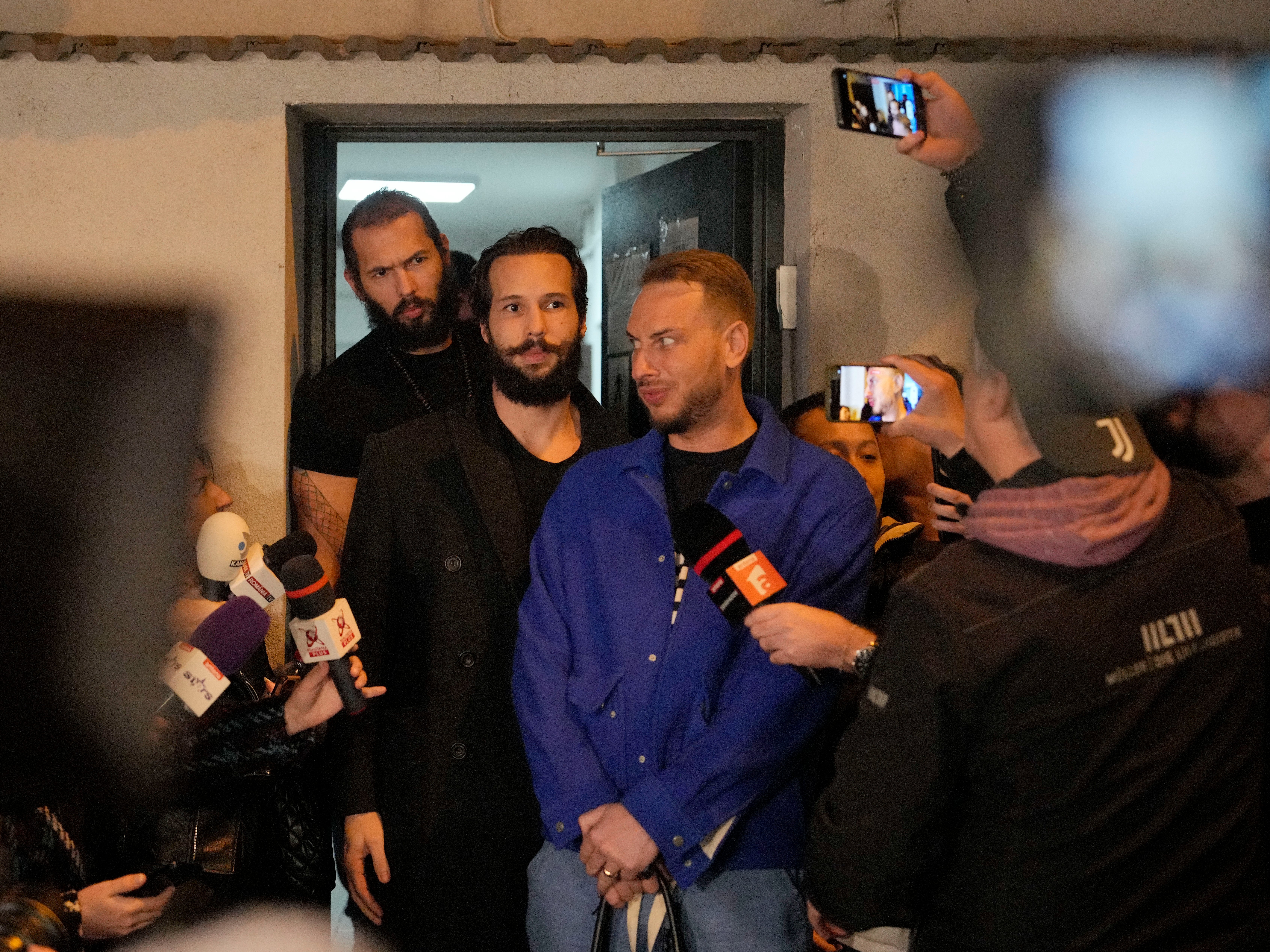 Andrew Tate, left, and his brother Tristan stand outside a police detention facility in Bucharest, Romania