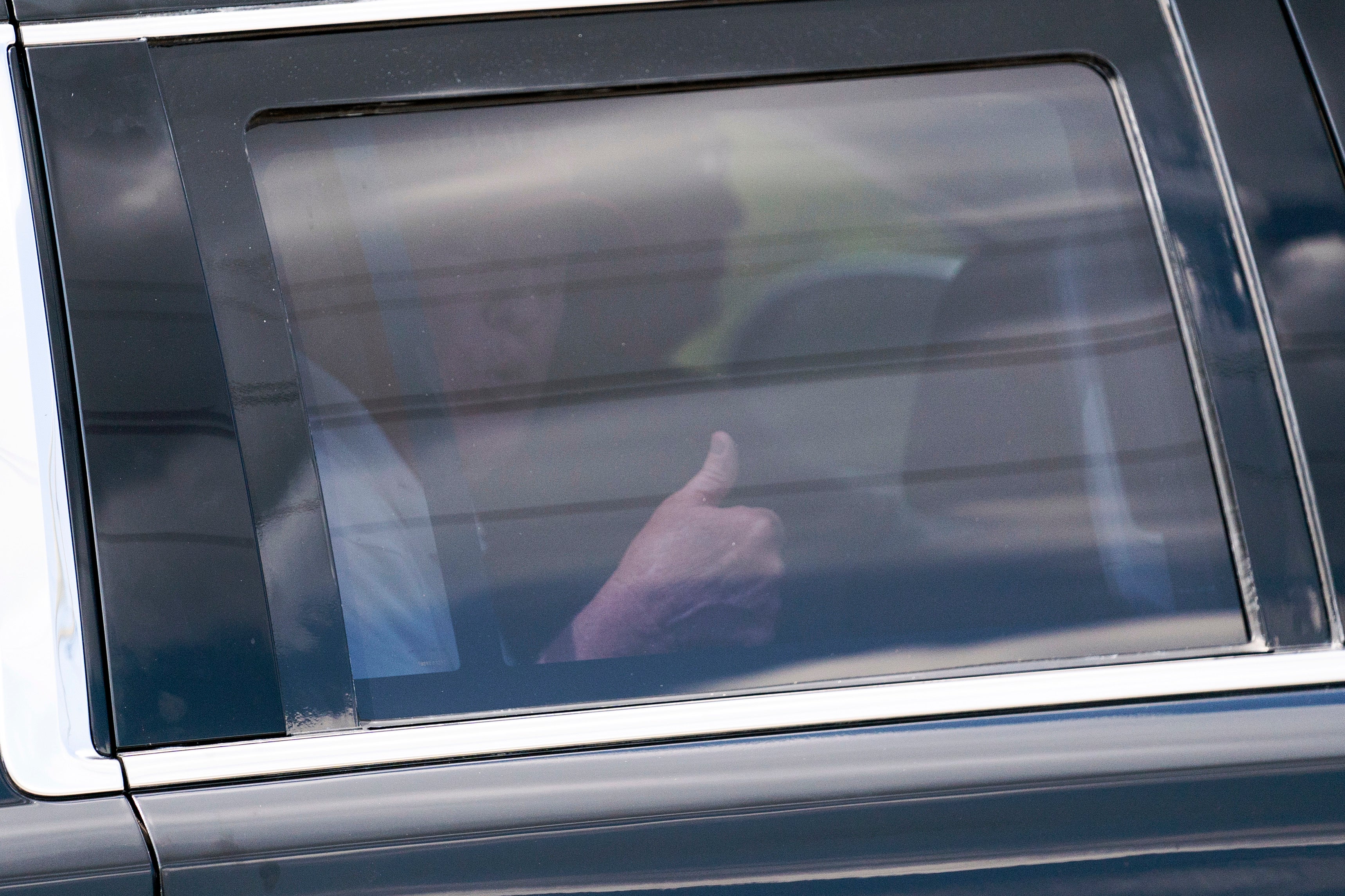 President Donald Trump gives a thumbs-up as he leaves Trump International Golf Club in his motorcade on Sunday 2 April