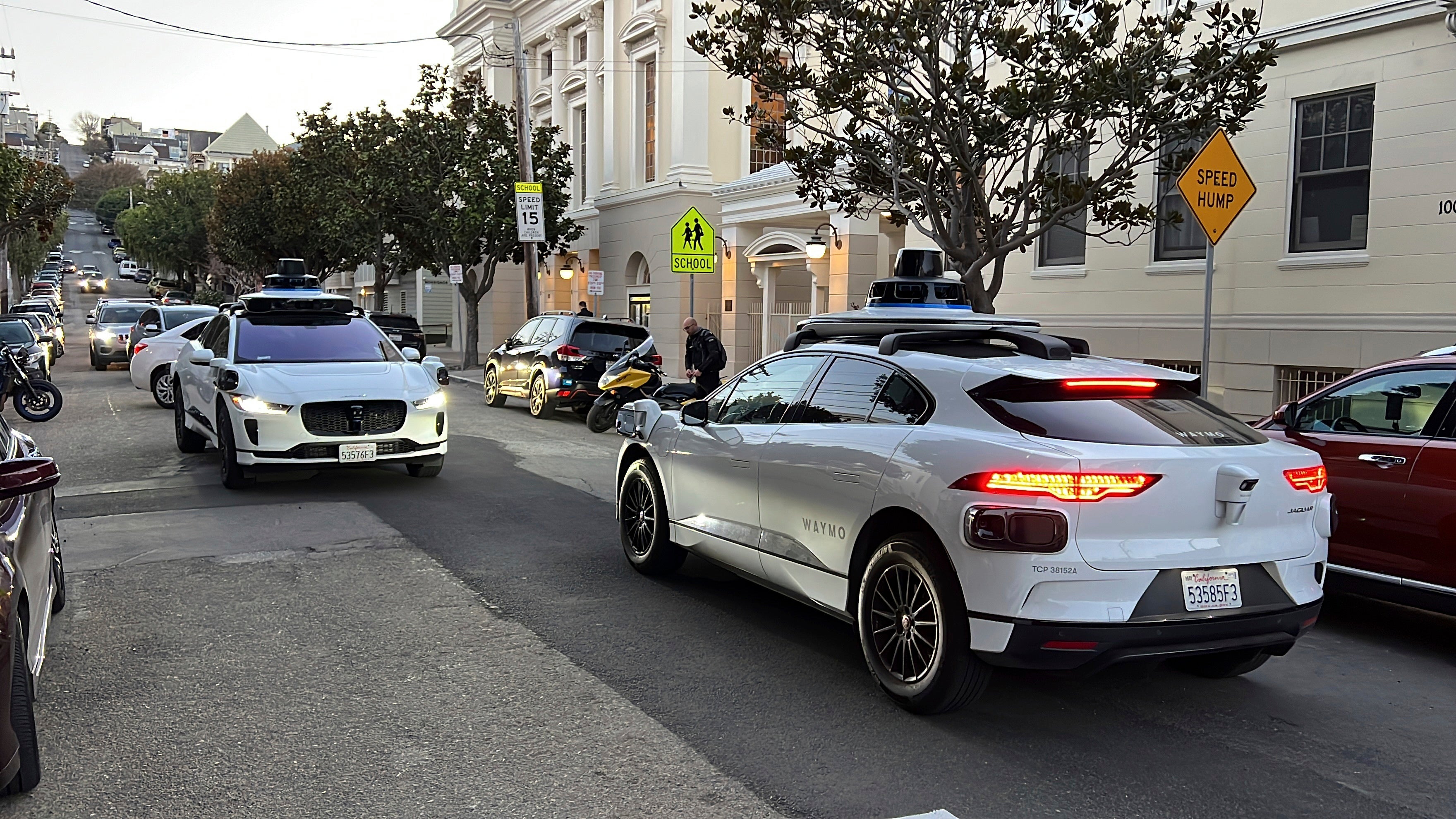 Two Waymo driverless taxis stop and face each other on a street in San Francisco before driving past each other in 2023