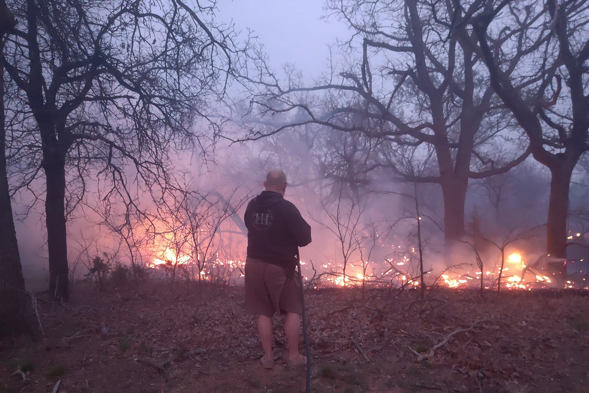 Jim Garinger, fights a fire outside his home built by his great-grandfather, March 31, 2023, in Guthrie, Oklahoma. Garinger and his family were able to save his family home with the help of firefighters. Extremely dry conditions in Oklahoma combined with high winds to fuel several large wildfires that forced interstate closures and sent residents fleeing from their homes (Jessica Garinger via AP)