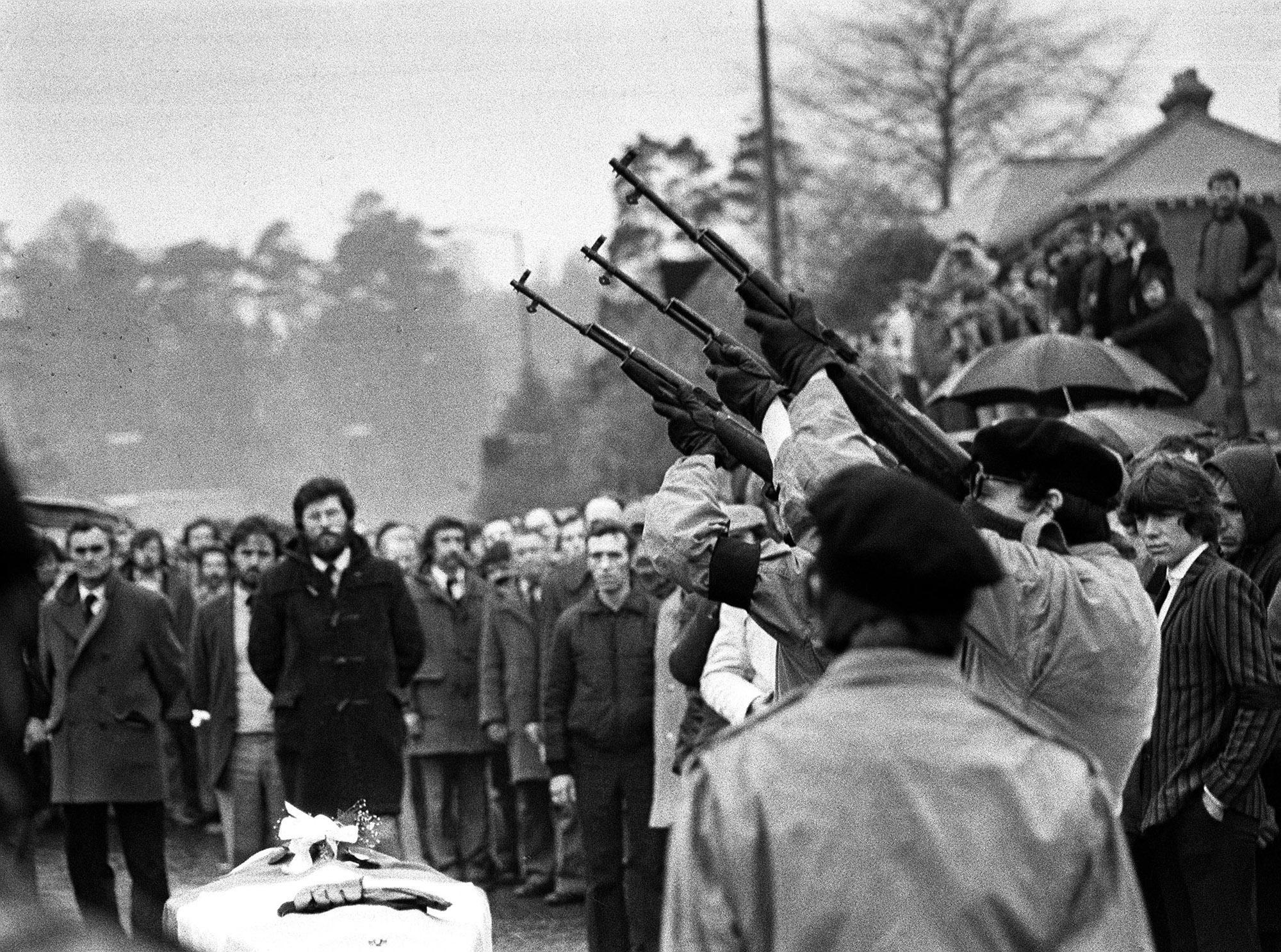 Masked men fire volleys of rifle shots in 1981 over the coffin of hunger-striker Bobby Sands