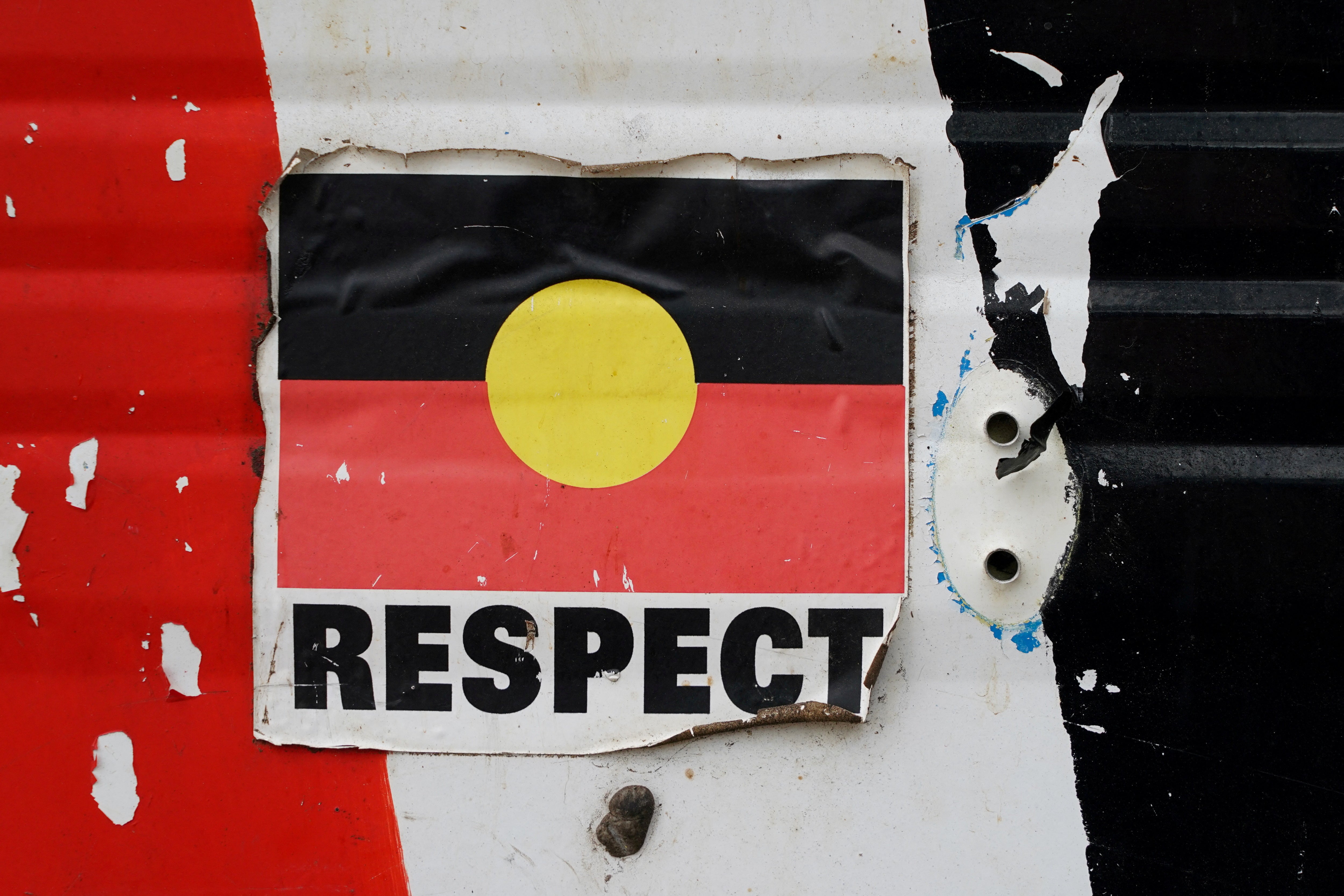 A sticker of the Australian Aboriginal Flag along with the word "RESPECT" is pictured on a structure at the Aboriginal Tent Embassy